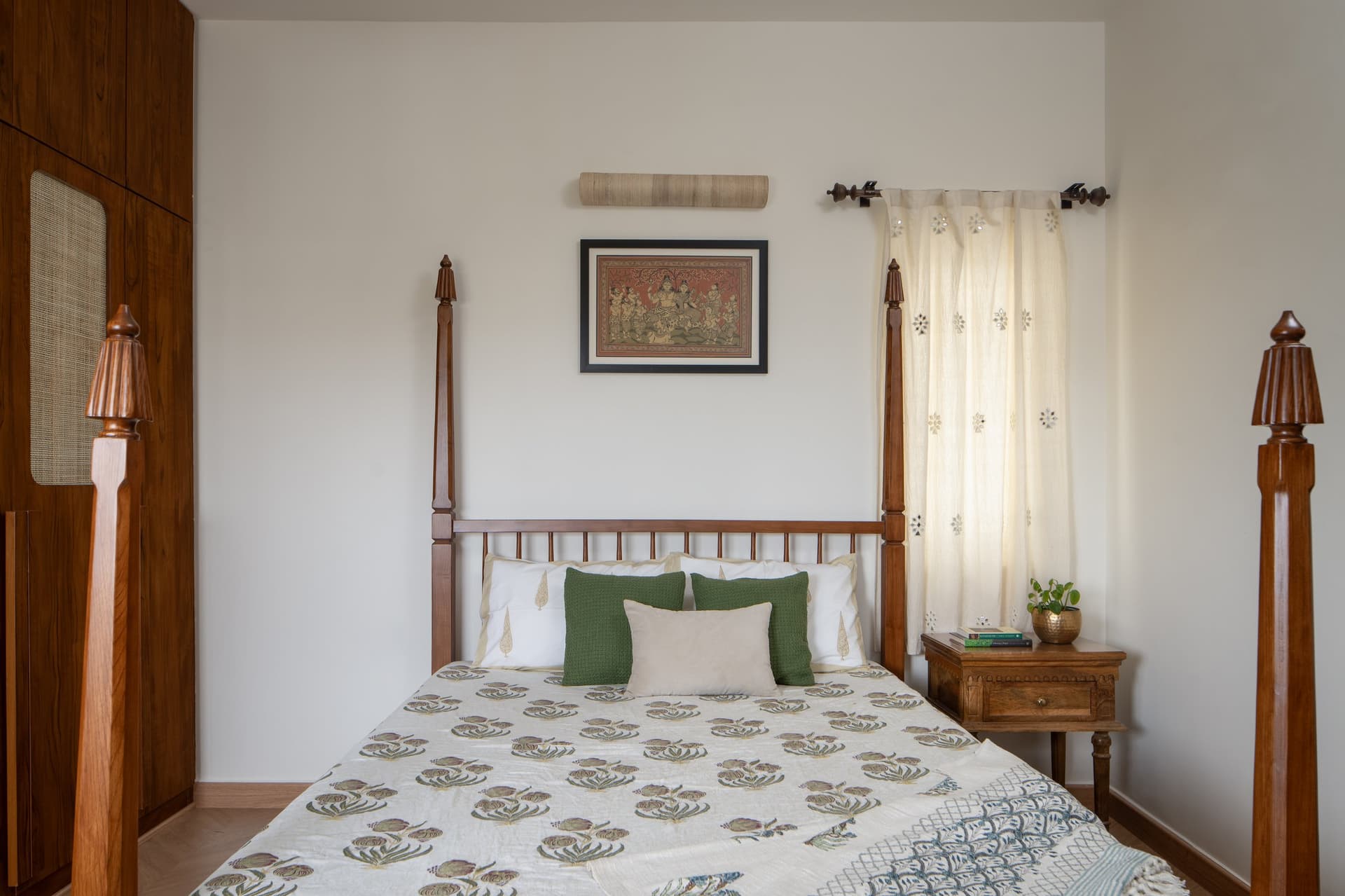 The bed seen head-on, framed by a single Pattachitra-style work that carries the room's cultural register