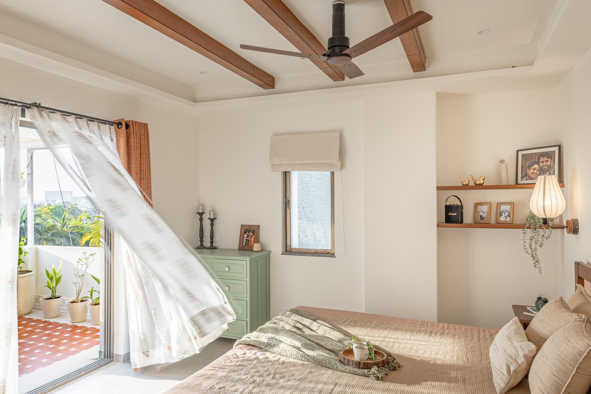 The primary bedroom balcony, patterned in terracotta tile and layered with potted greenery
