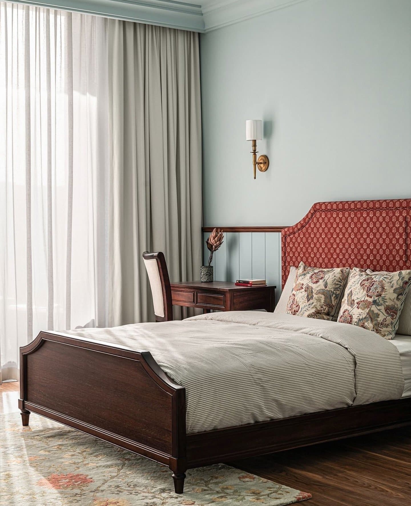The bedroom, where a carved mahogany bed frame meets a red block-print headboard.