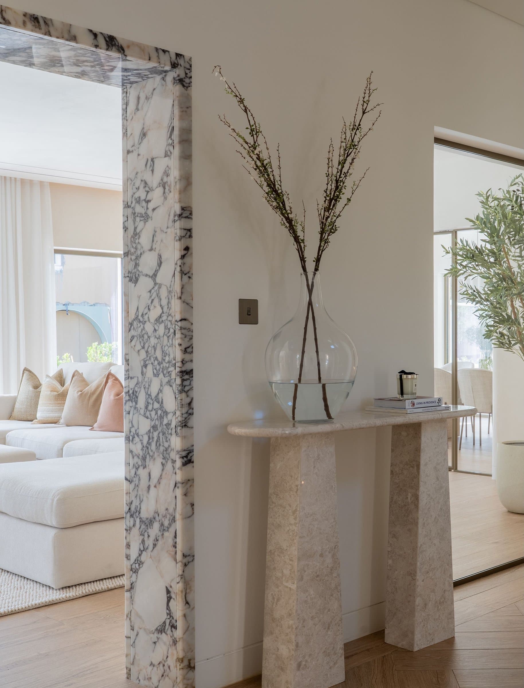A veined marble threshold in the foyer wraps into a faceted console table.