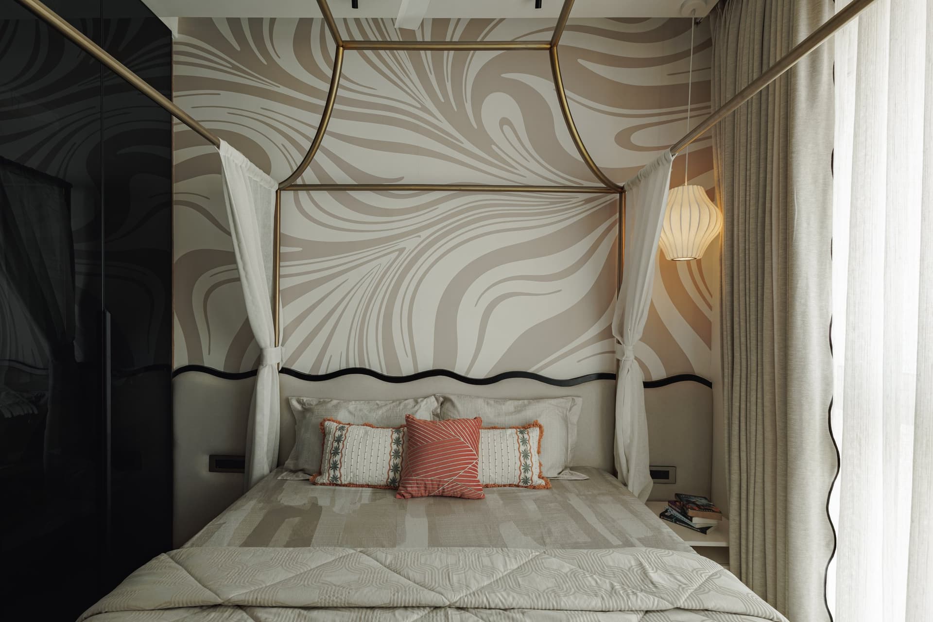 A bedroom in softer graphic territory, its swirling pale mural set behind an upholstered headboard with a dark undulating trim