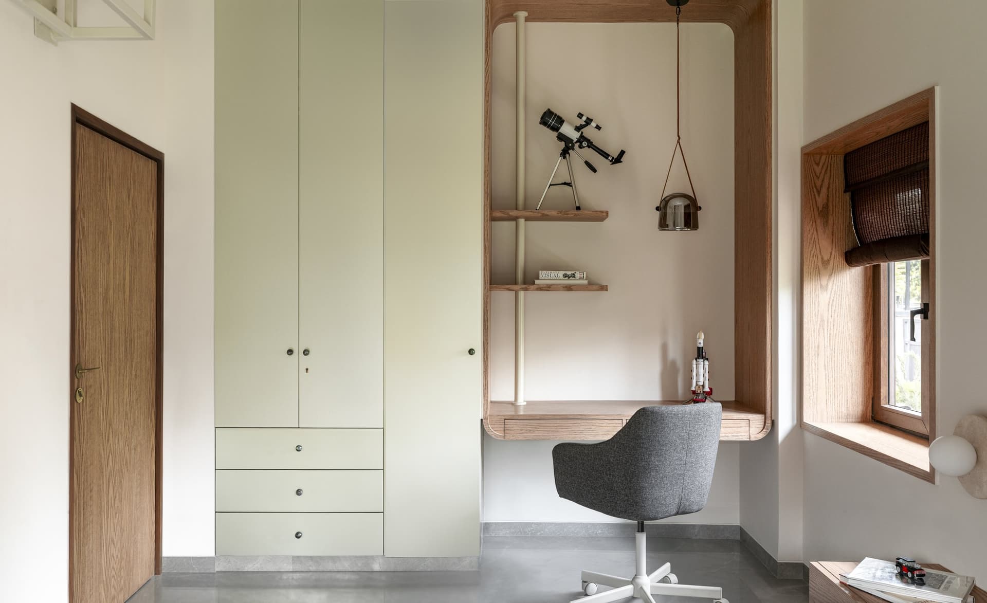The child's room, with a built-in desk niche in warm timber paired with a full-height pale wardrobe