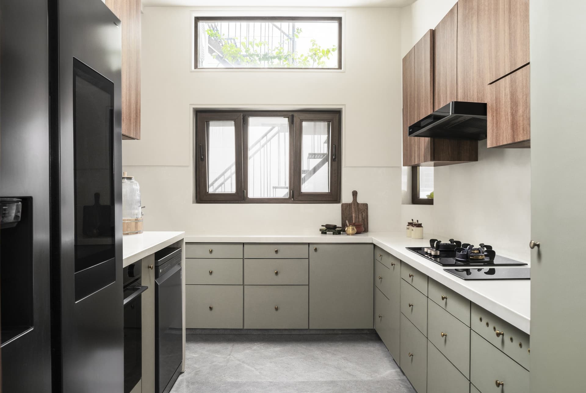 The kitchen, where muted sage cabinetry and warm-toned upper units meet timber-framed windows