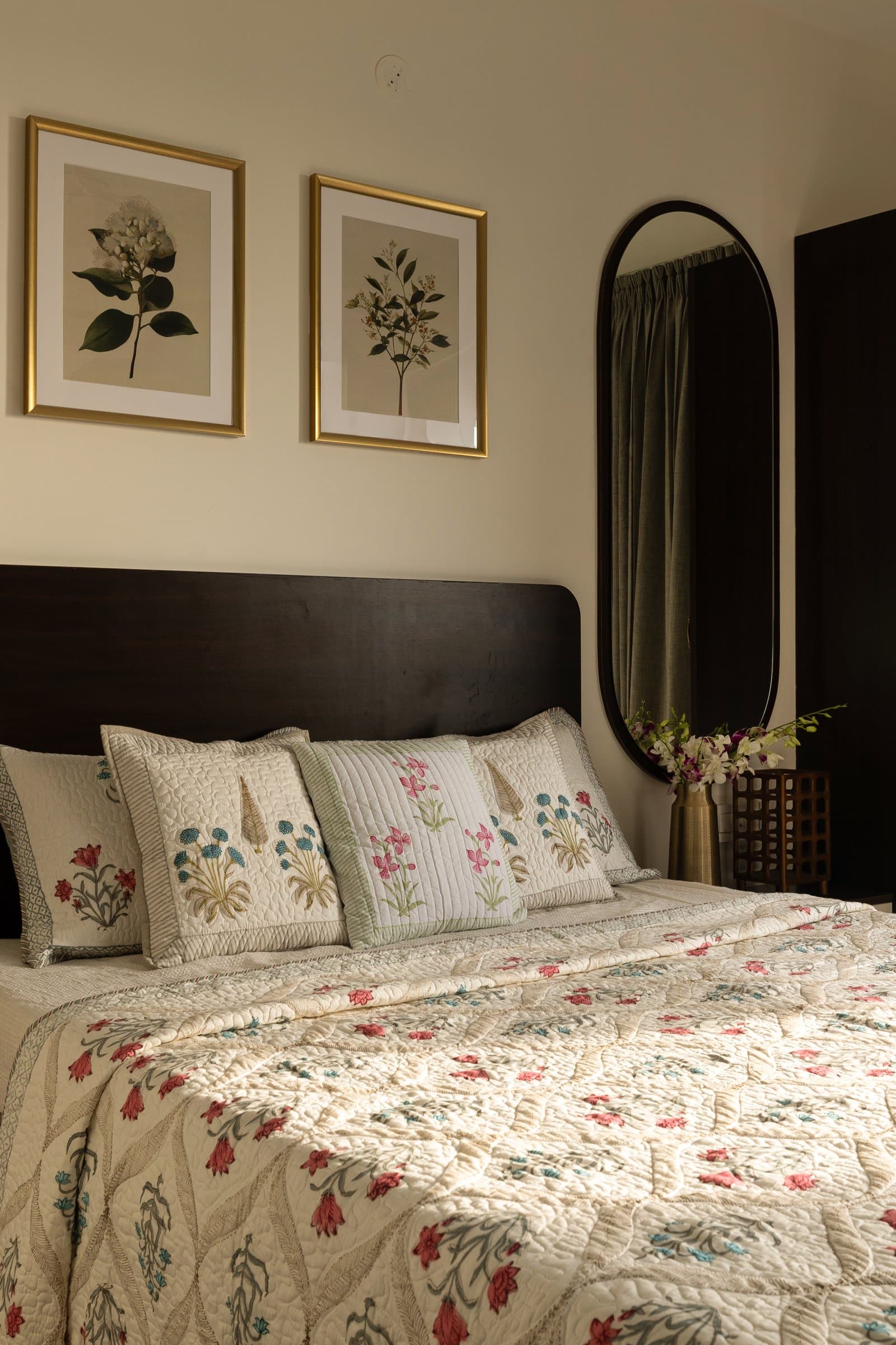The second bedroom, quieter and closer to a guest room, with botanical prints above a dark headboard