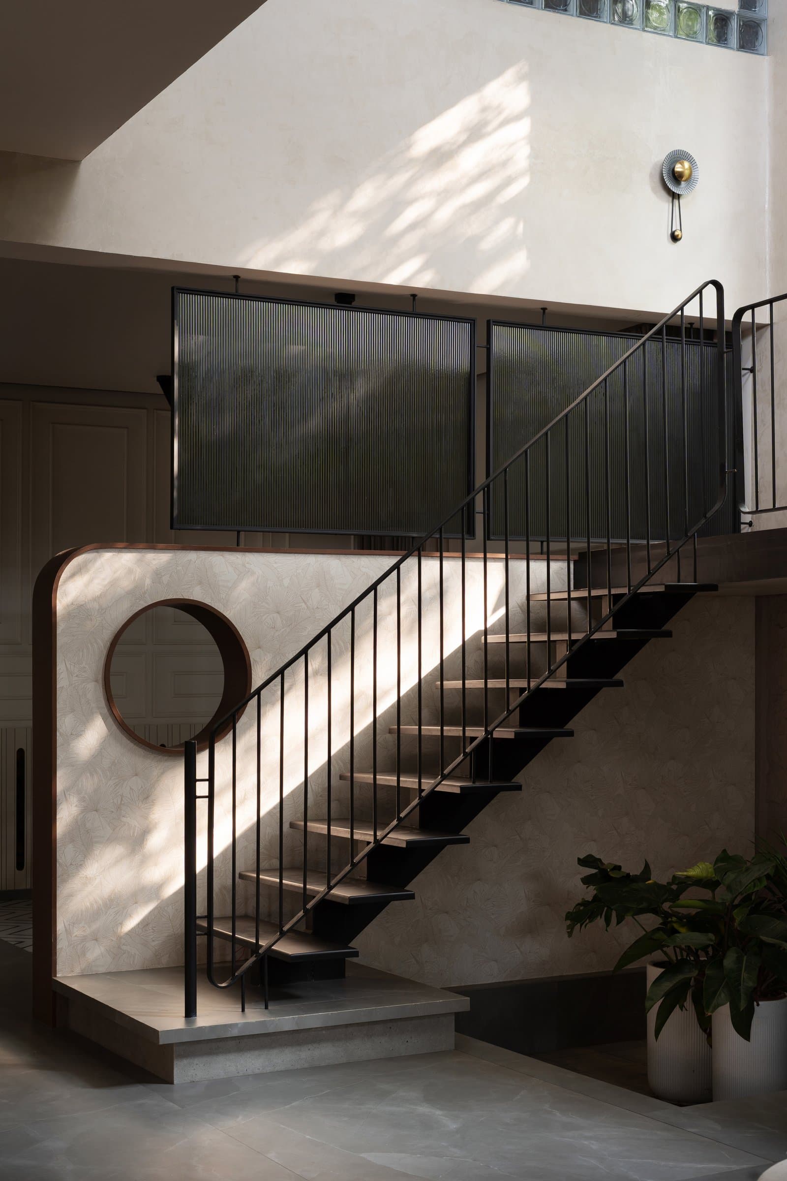 The staircase, cantilevered from a blackened steel stringer beneath a reeded-glass balustrade