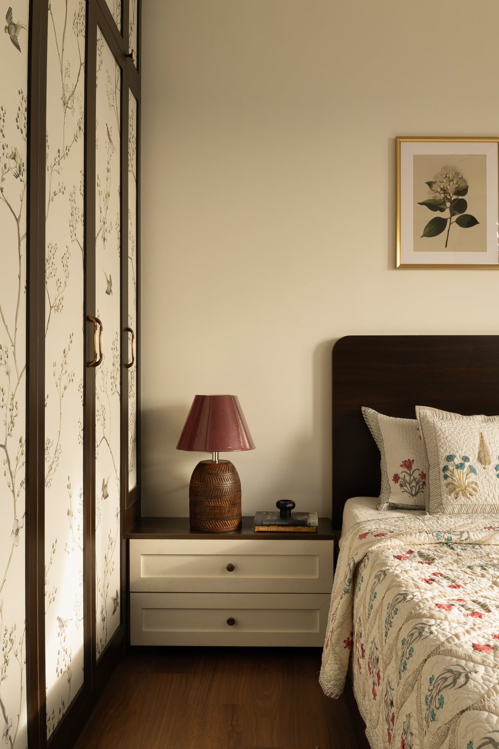 The bedside composition, where a cream drawer unit meets the wardrobe's dark frame above a warm wooden floor