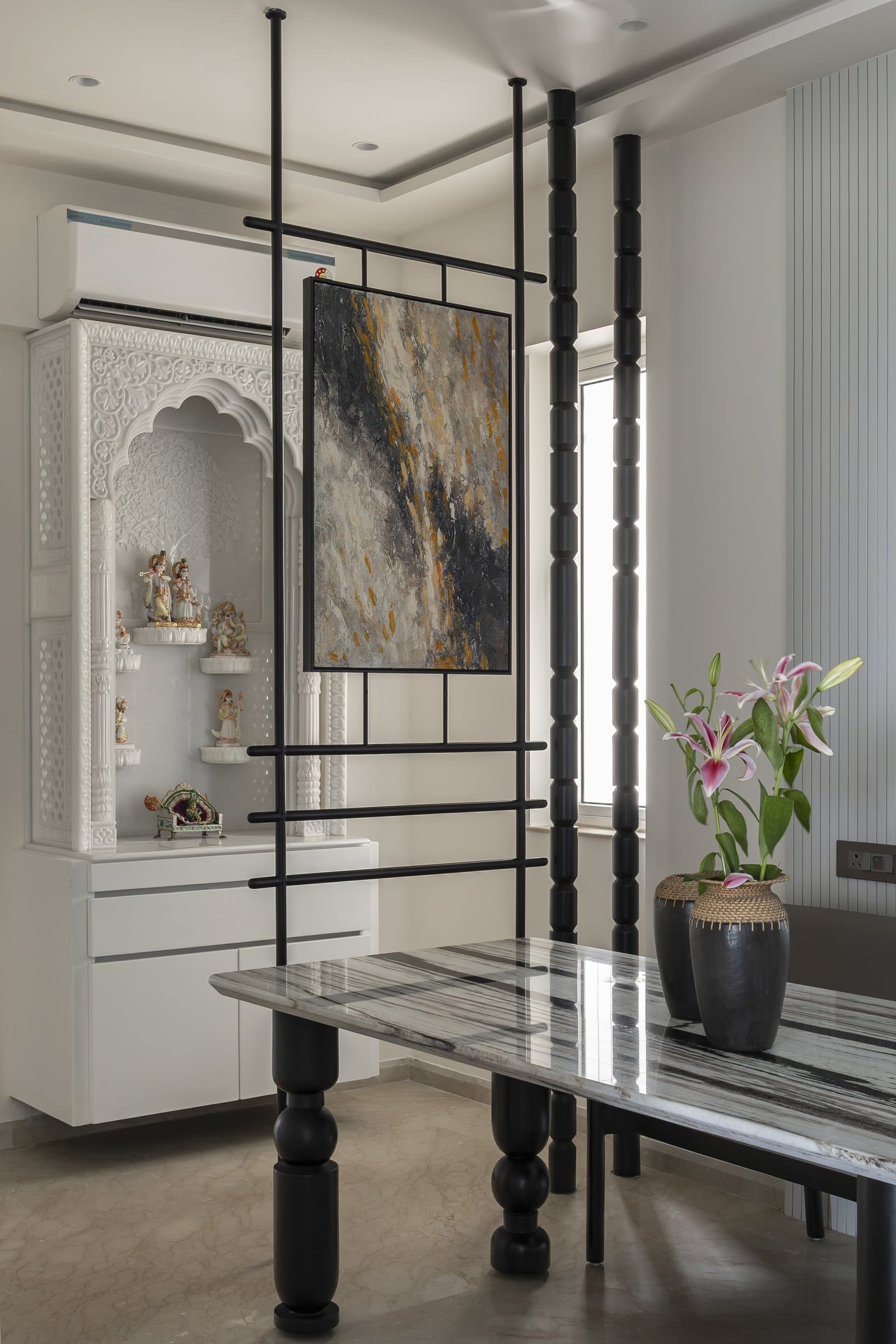 The puja enclosure, framed by a black metal grille and slender turned columns that act as a semi-transparent screen