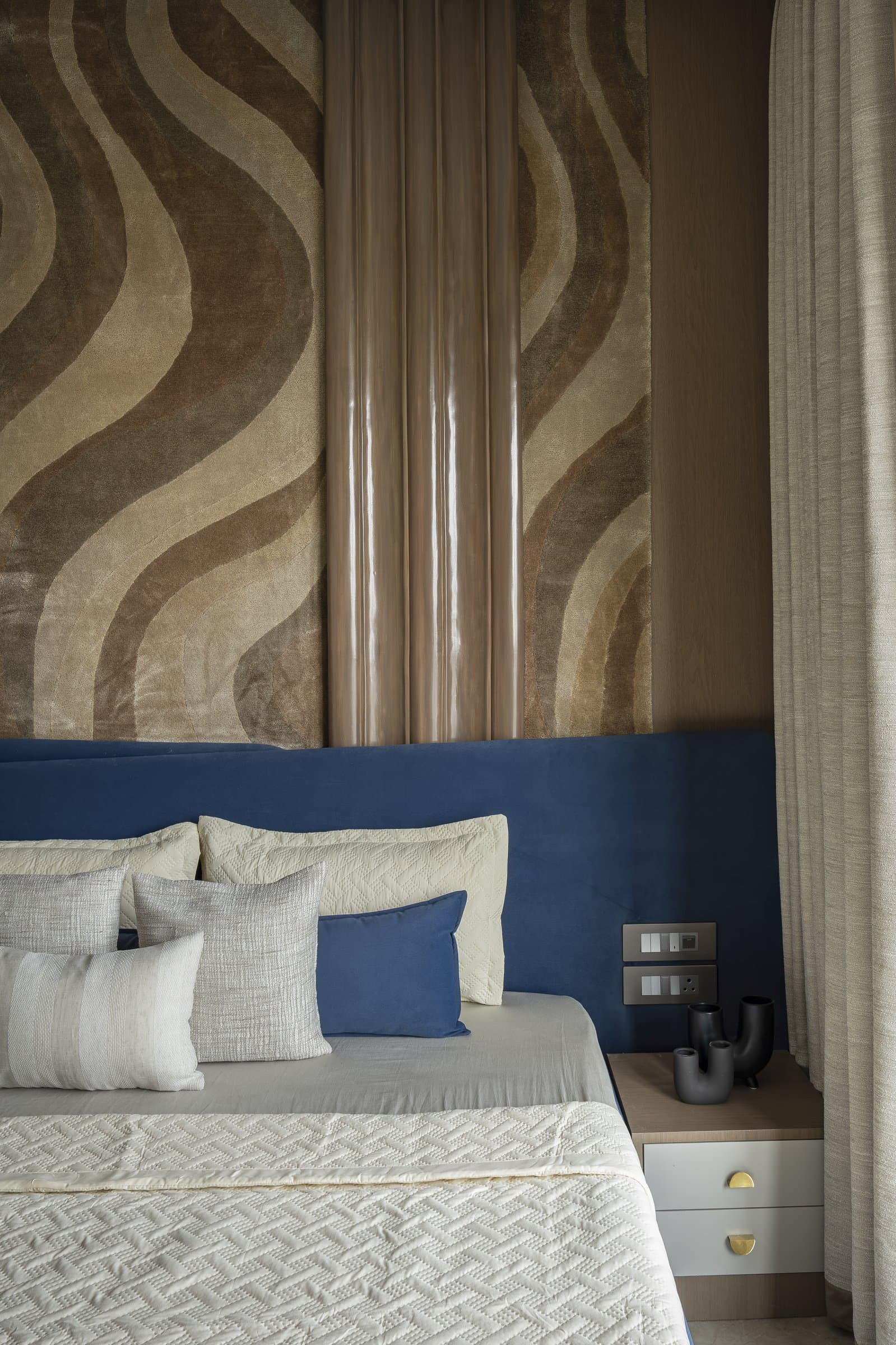 A polished veneered panel runs between the two rug sections, introducing controlled luxury against the textile's handwork
