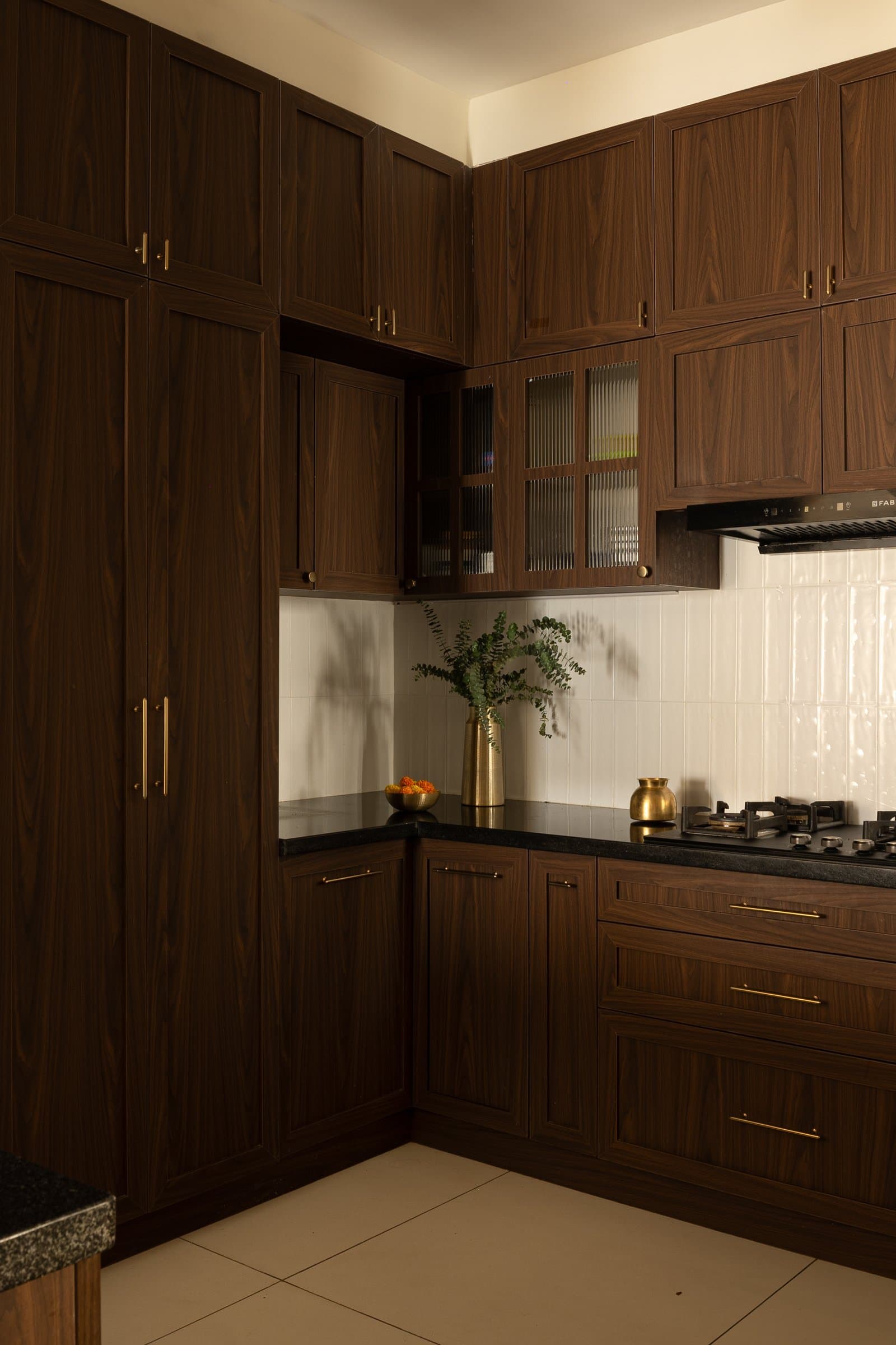 The working kitchen, a disciplined pairing of dark wood cabinetry and a pale vertical-tile backsplash