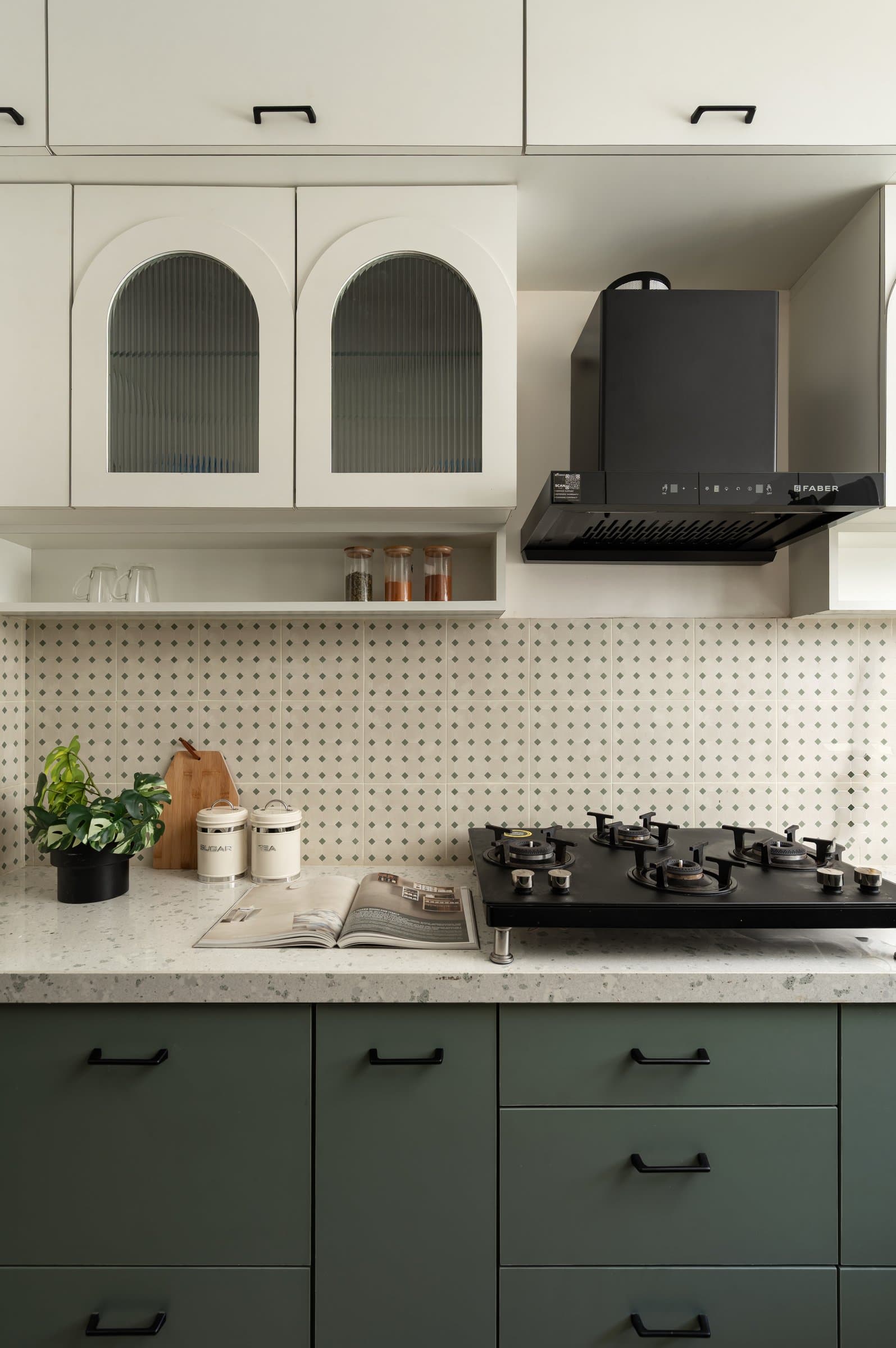 The kitchen, where sage-green lower cabinetry grounds a composition of ivory uppers and a patterned backsplash