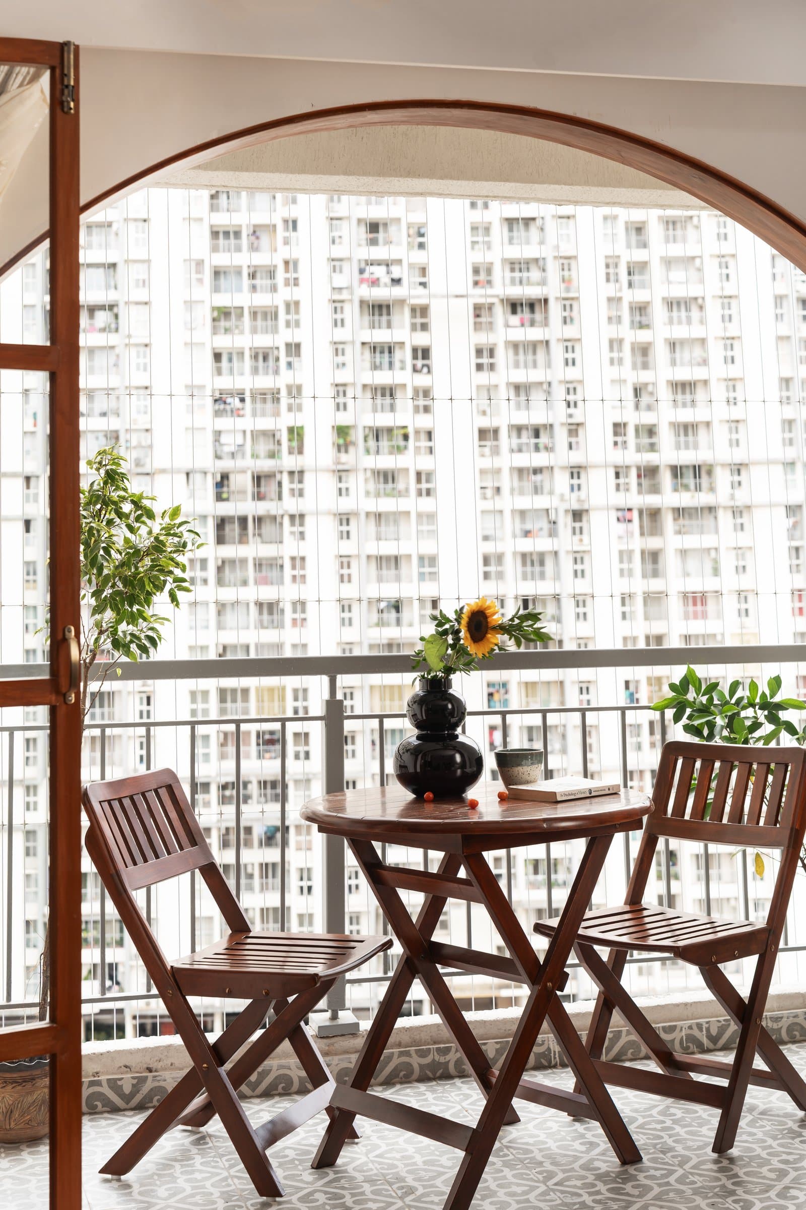 The balcony, where a wooden bistro set sits against patterned cement tiles beneath an arched doorway