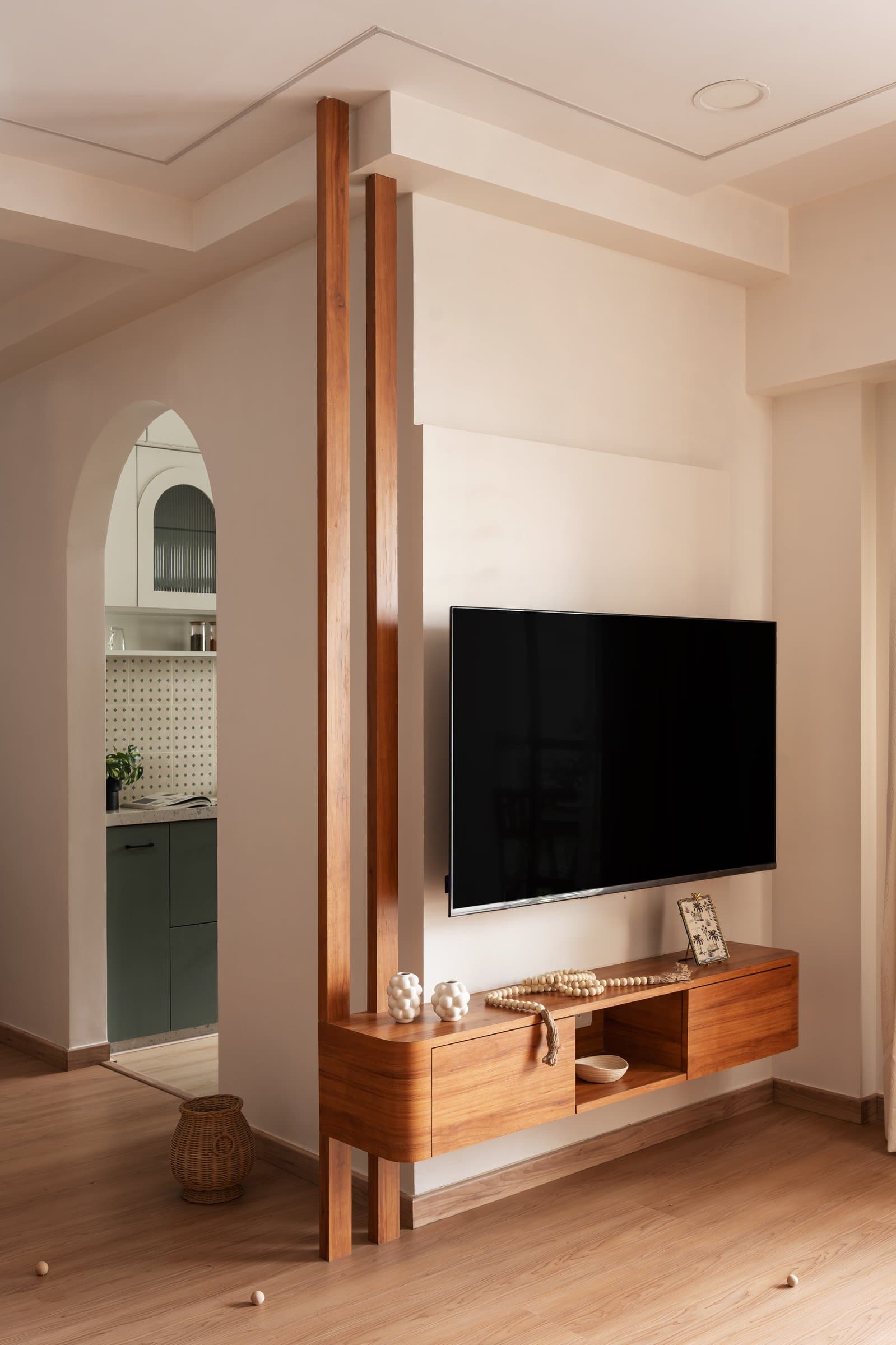 Slender wooden fins frame the threshold between living and kitchen, carrying a floating media console