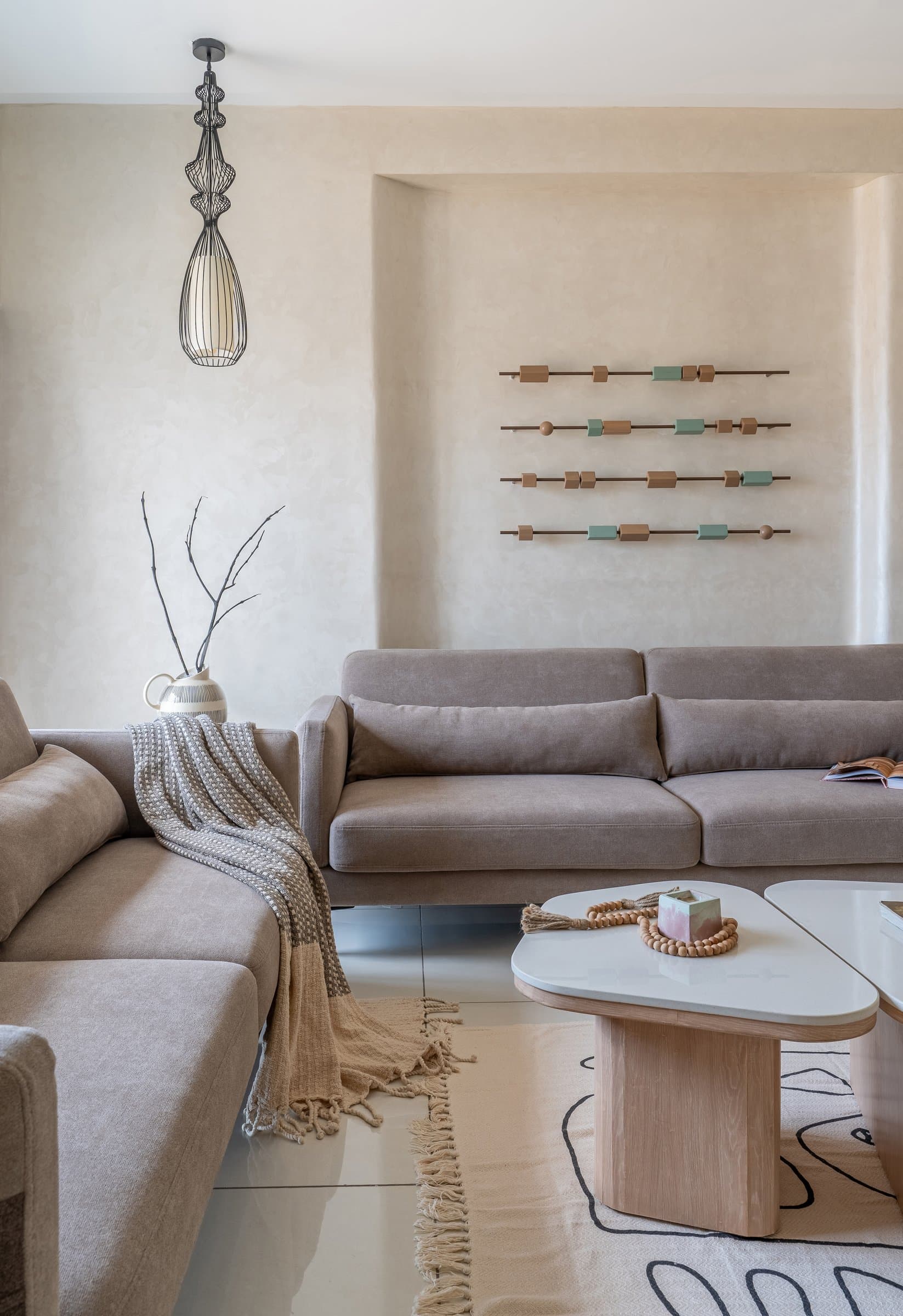 A closer view of the living room, where a sculptural wire-form pendant and an abacus-like wall composition offer measured graphic counterpoints