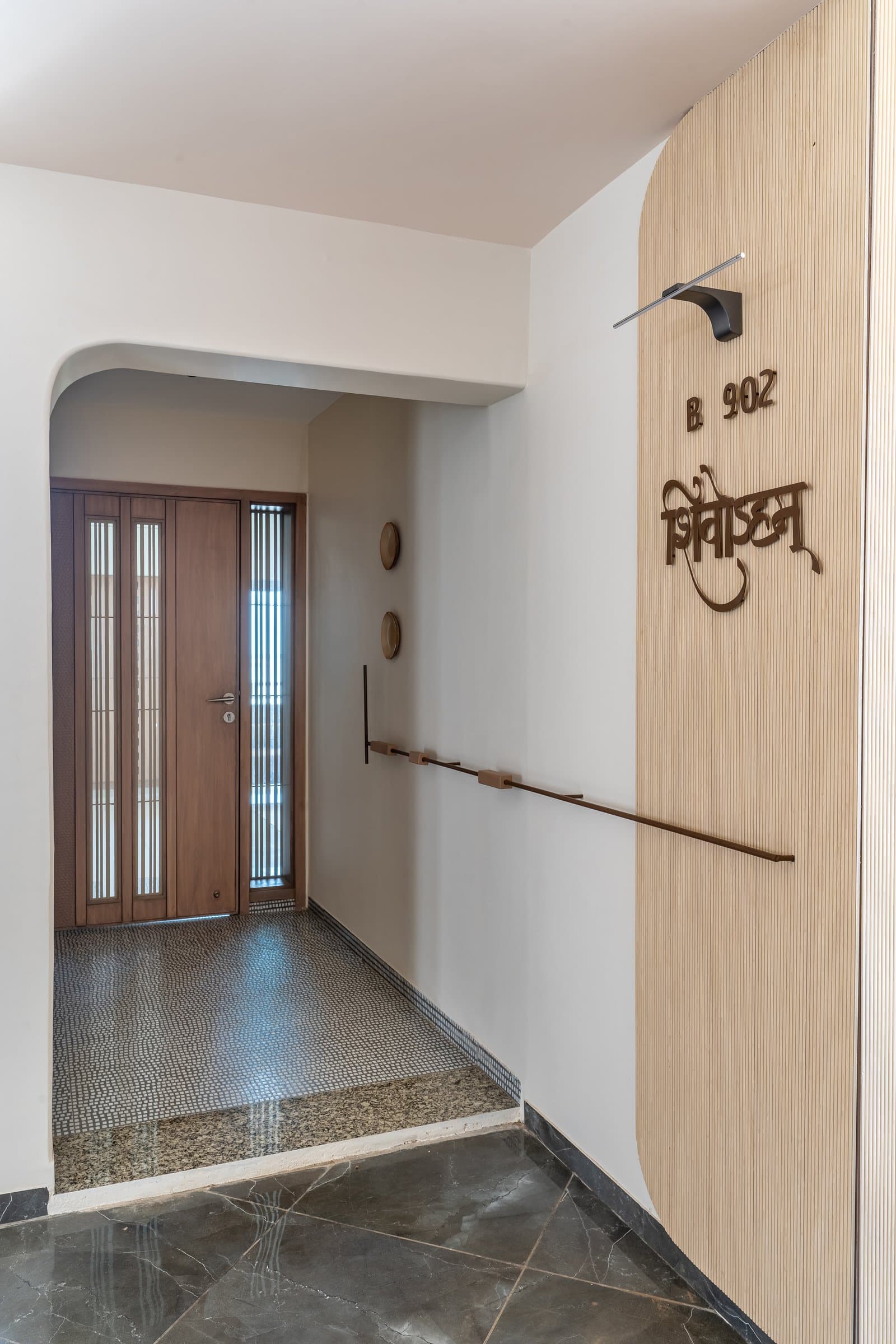 The foyer, where vertical reeding and a wooden door with slender glazed inserts establish the home's quieter welcome