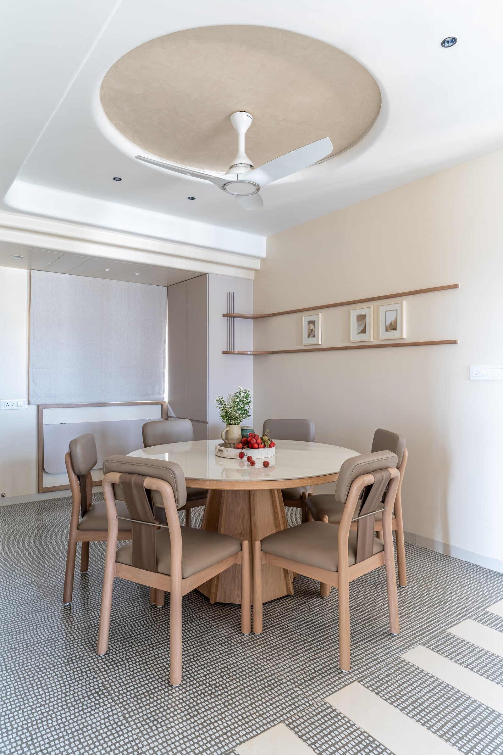 The dining area, composed around a round pedestal table and a circular ceiling detail that echoes its geometry