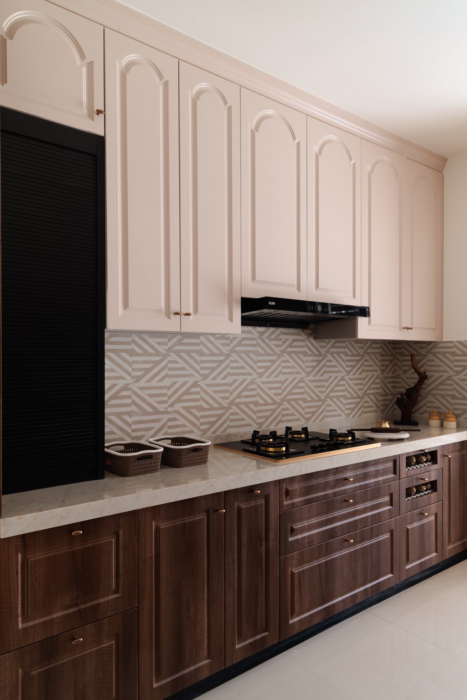 The kitchen pairs warm wooden lowers with soft ivory arched uppers, a geometric backsplash tying the two registers together