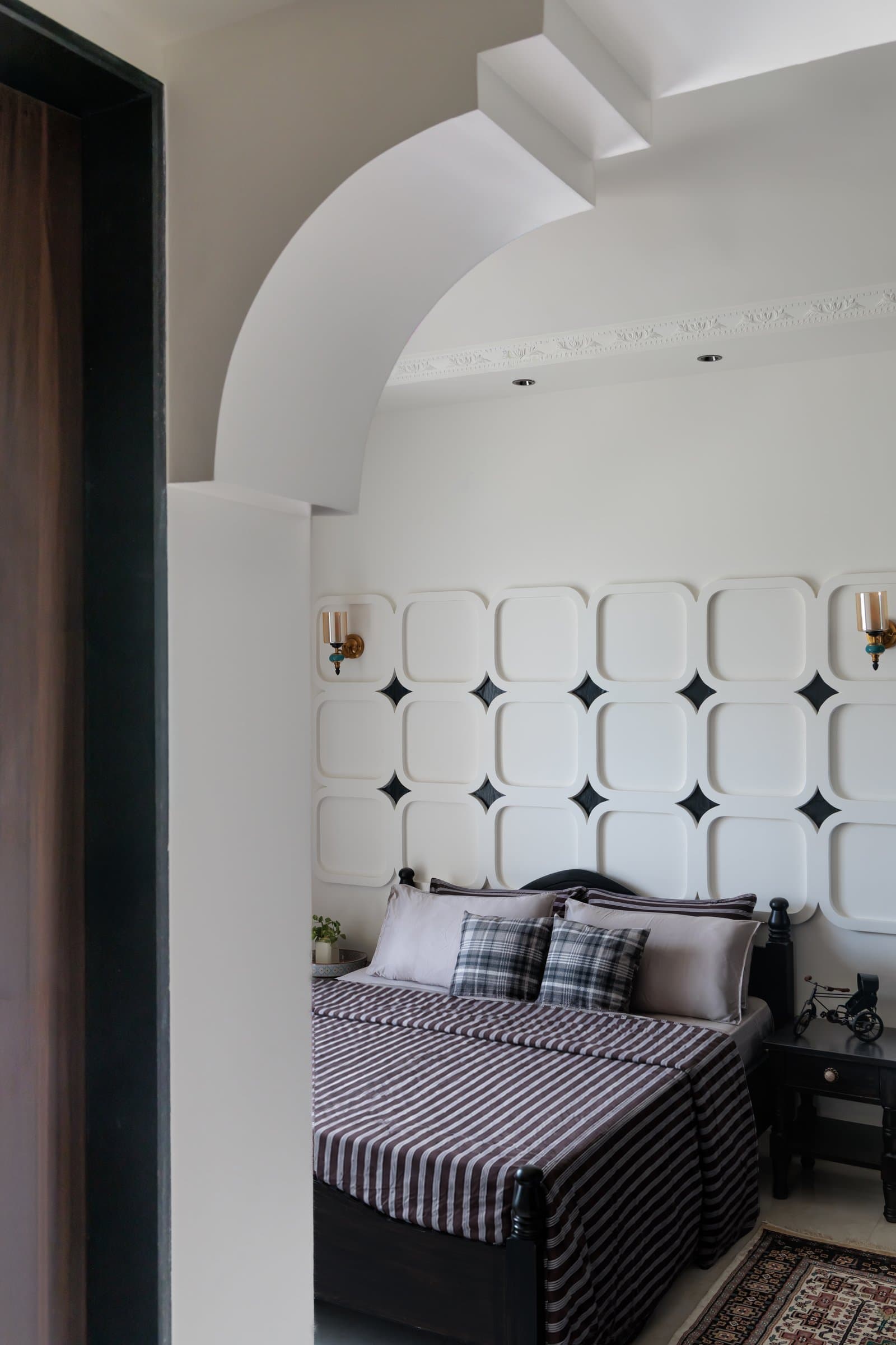 The guest bedroom's headboard wall, where rounded panels with diamond inserts form the home's most pronounced architectural moment