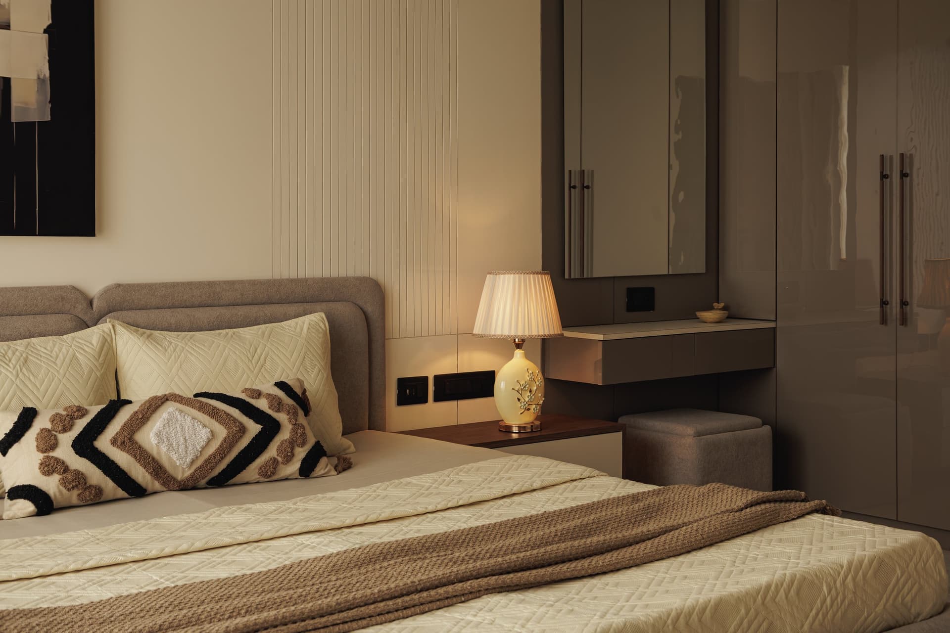 The storage wall of the second bedroom, where high-gloss taupe wardrobes meet a floating desk-console
