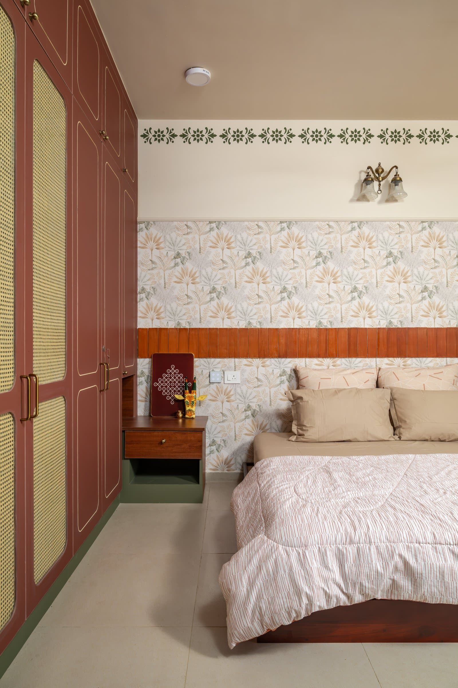 The primary bedroom, where a terracotta wardrobe wall and a slatted wooden headboard anchor a patterned wall composition