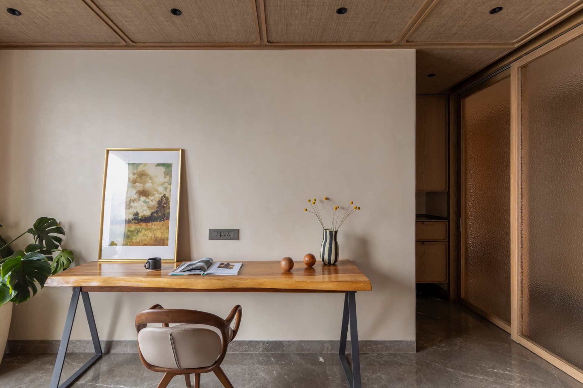 The study, defined overhead by a woven cane ceiling framed in slim wooden battens