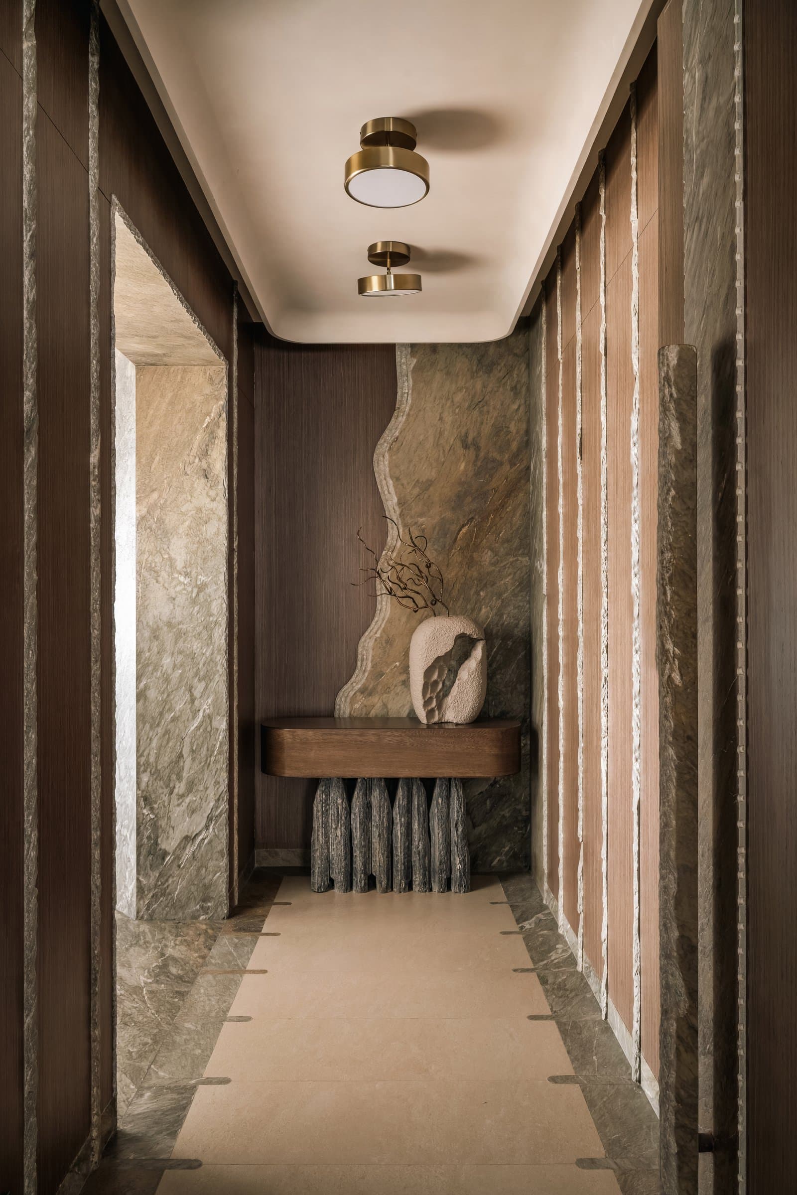 The foyer, where a hand-chipped marine-green marble slab backs a sculptural slate-and-veneer console