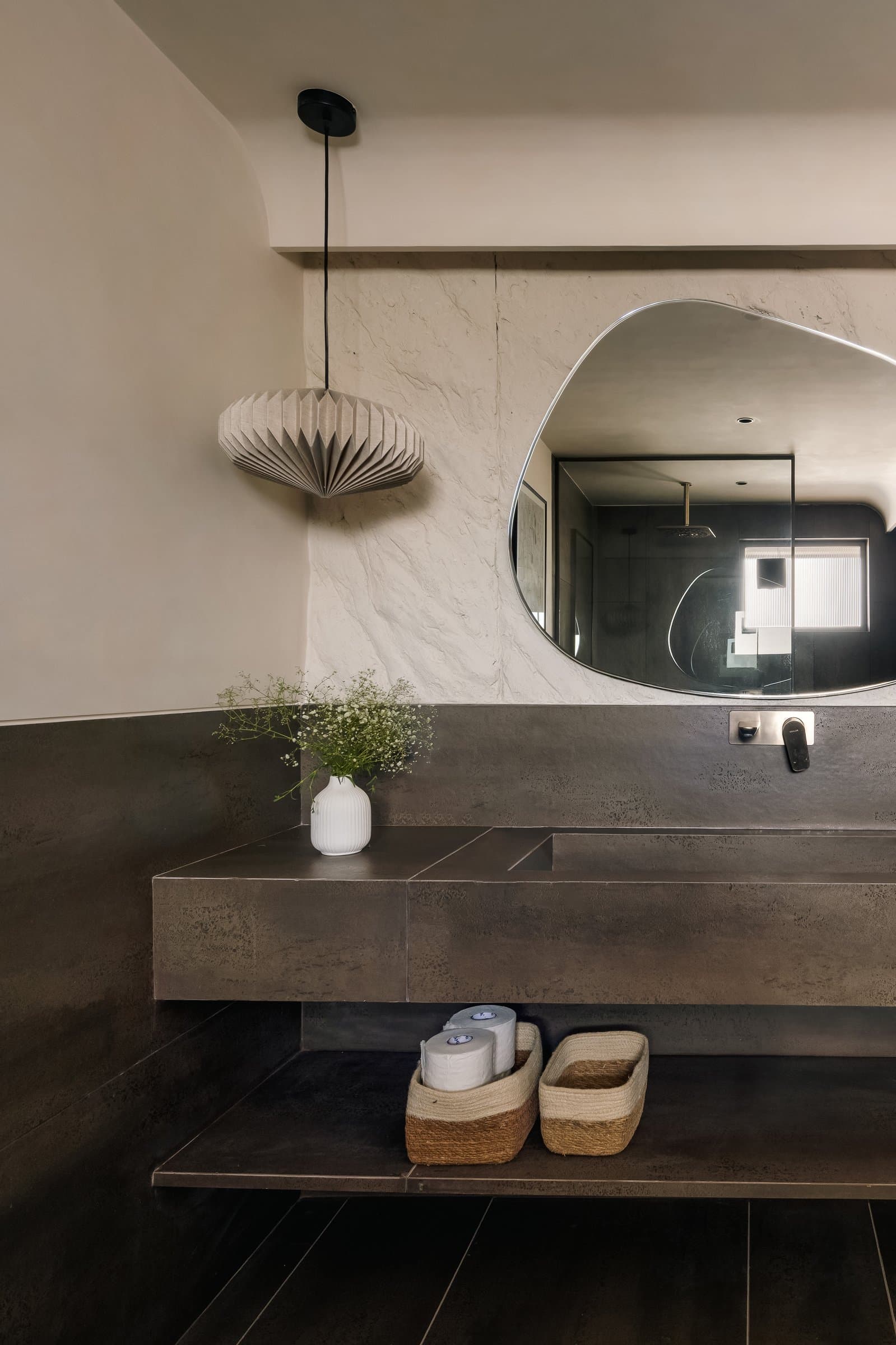 The powder bathroom, where a dark metallic vanity cantilevers from a rough-plastered wall