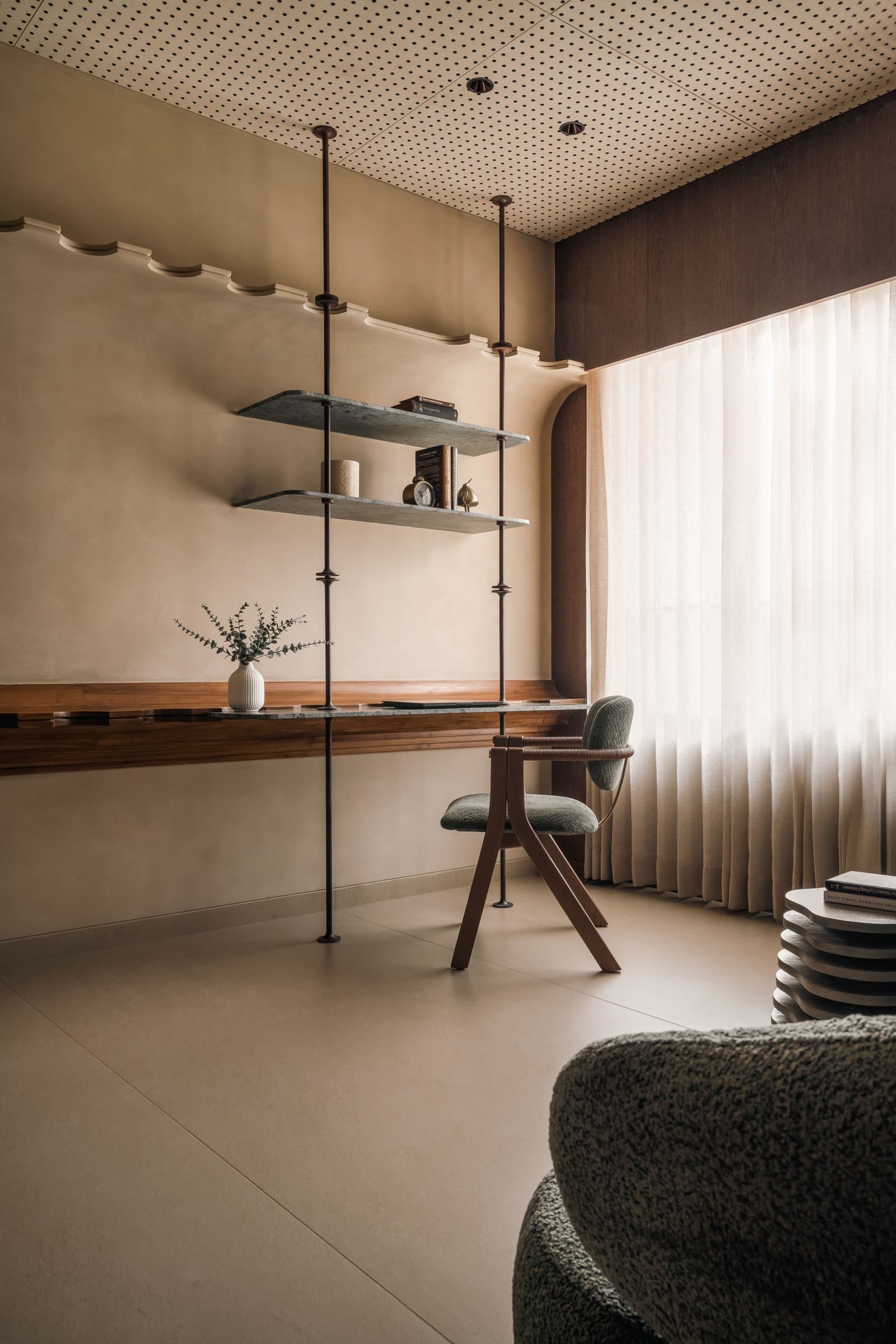 The study nook, with a green marble desk and vertical metal rods set beneath an undulating cornice