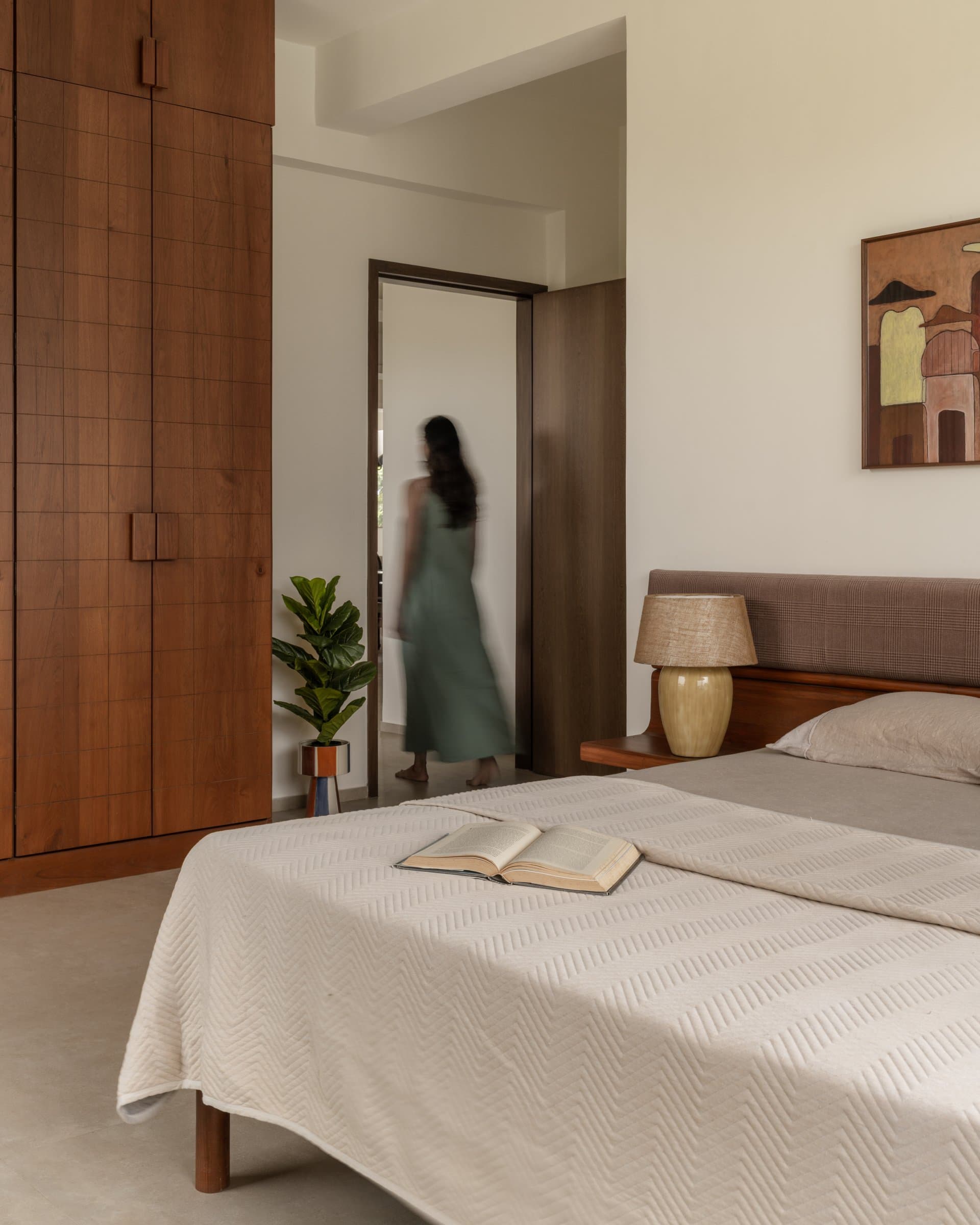 The wardrobe wall holds the room with quiet weight while the doorway opens back toward the living areas