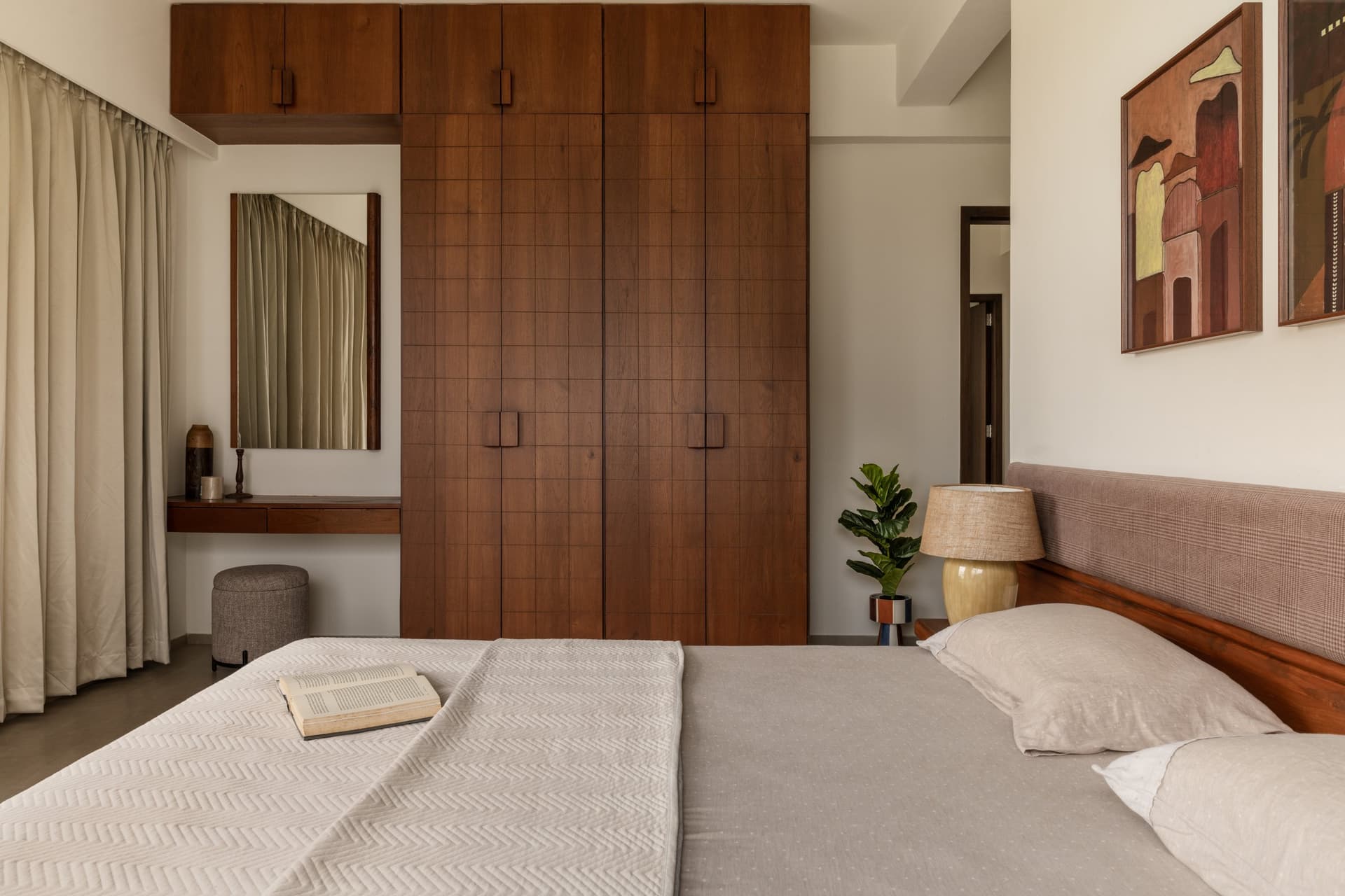The primary bedroom, organised around a tall wall of gridded wooden wardrobes with a dressing recess alongside