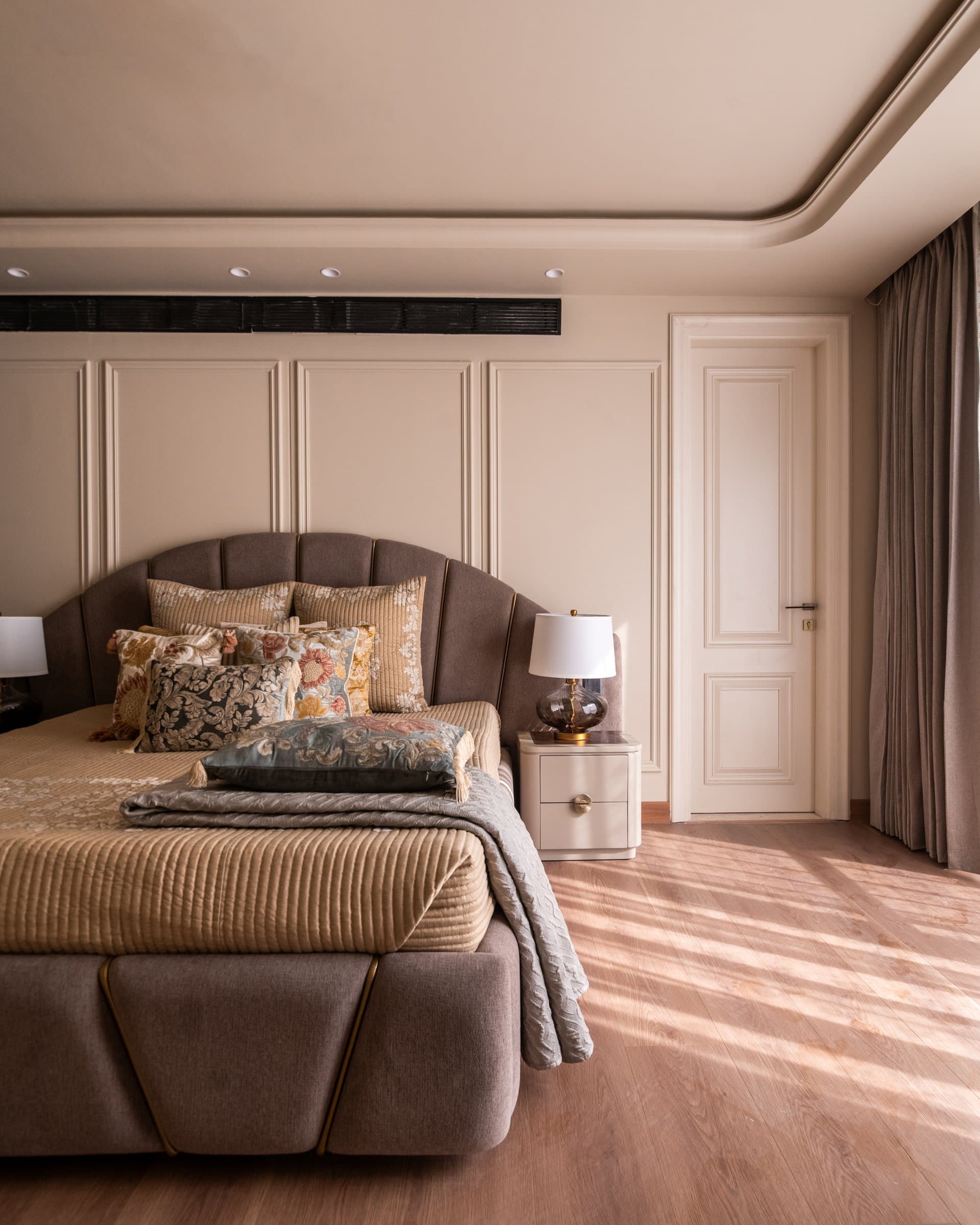 A second bedroom suite, extending the master's language of panelled walls and a shell-backed upholstered headboard
