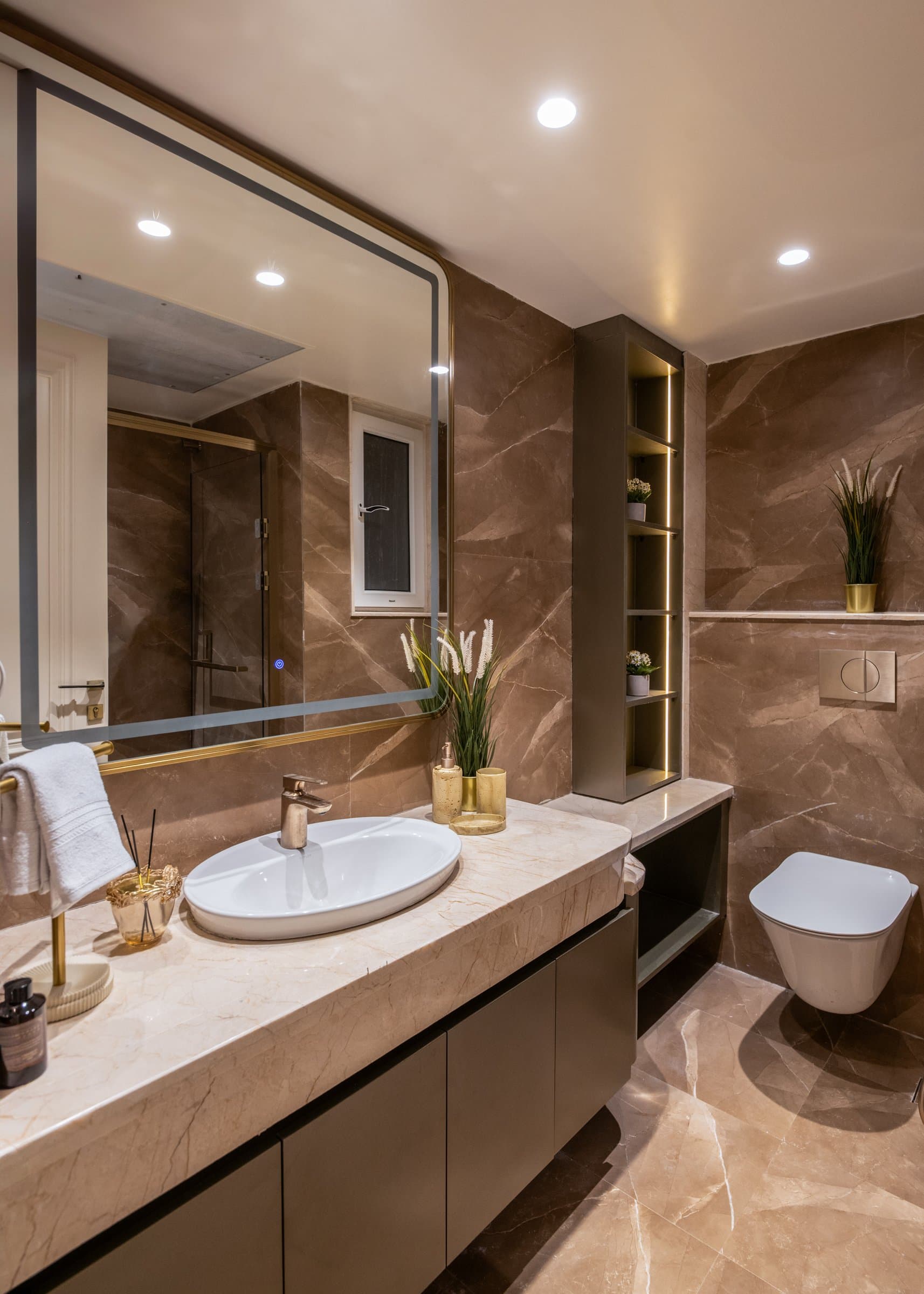 The master bathroom, where warm-toned stone slabs and a backlit niche compose a hotel-calibre retreat
