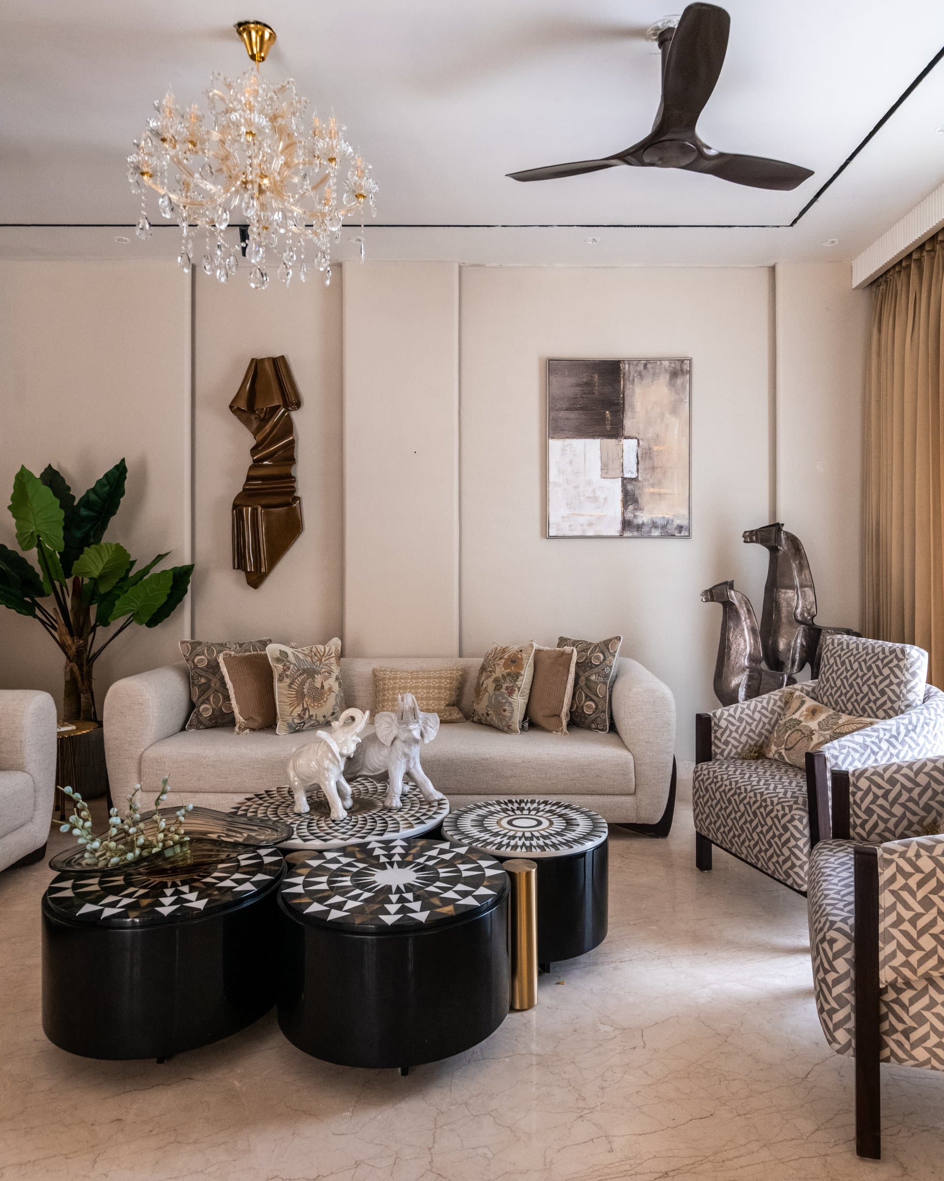 The formal living room, where twin sofas and a cluster of inlaid ottoman-tables orchestrate a layered but composed social arrangement