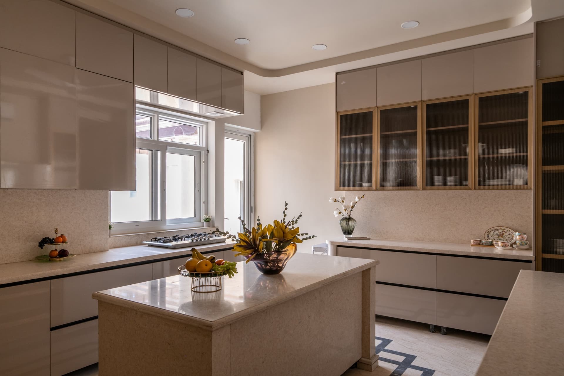 The kitchen in full, revealing its paired islands and the slim graphic inlay that threads geometry through the floor