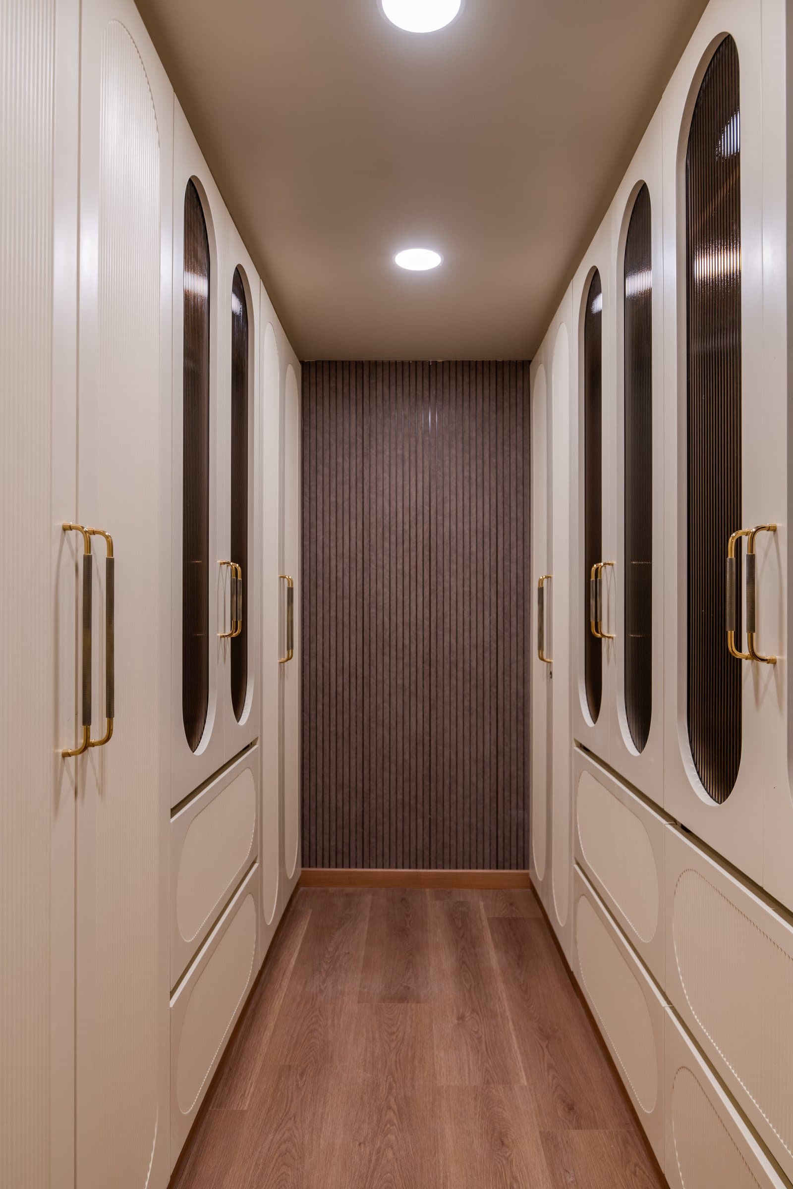 The walk-in wardrobe between master and bath, its arched fluted-glass fronts creating a disciplined architectural passage