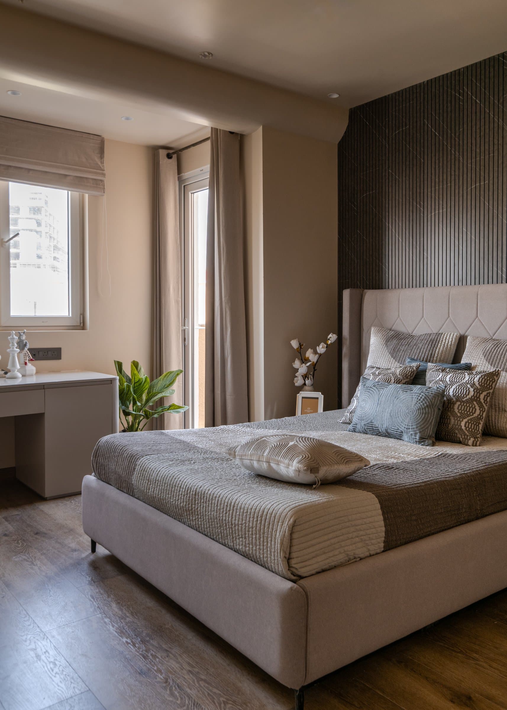A guest bedroom where a diagonally veined dark stone accent wall anchors the composition behind the upholstered headboard