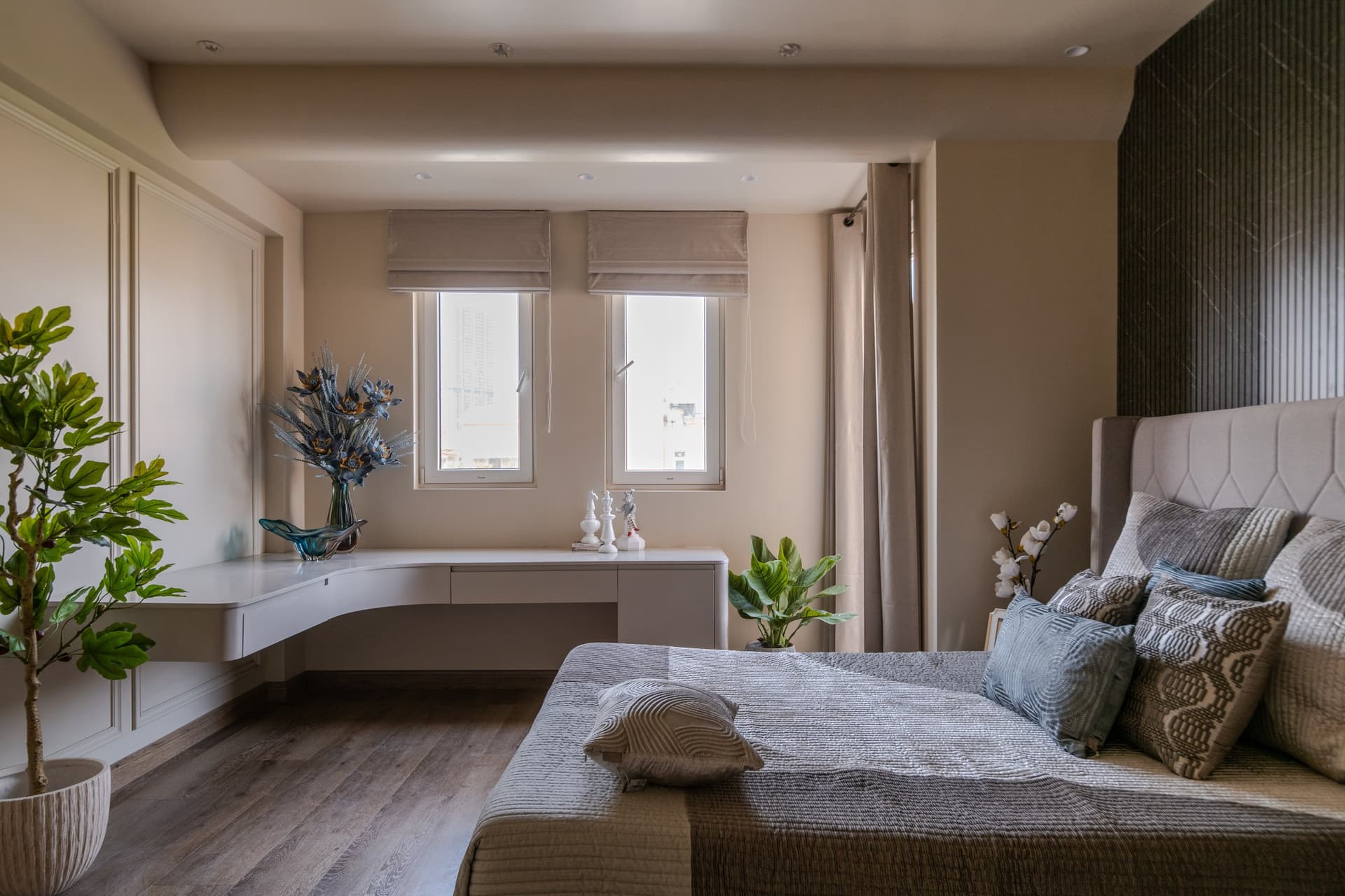 A wider frame of the same room, balancing the stone feature wall against panelled wardrobes and a built-in curved desk