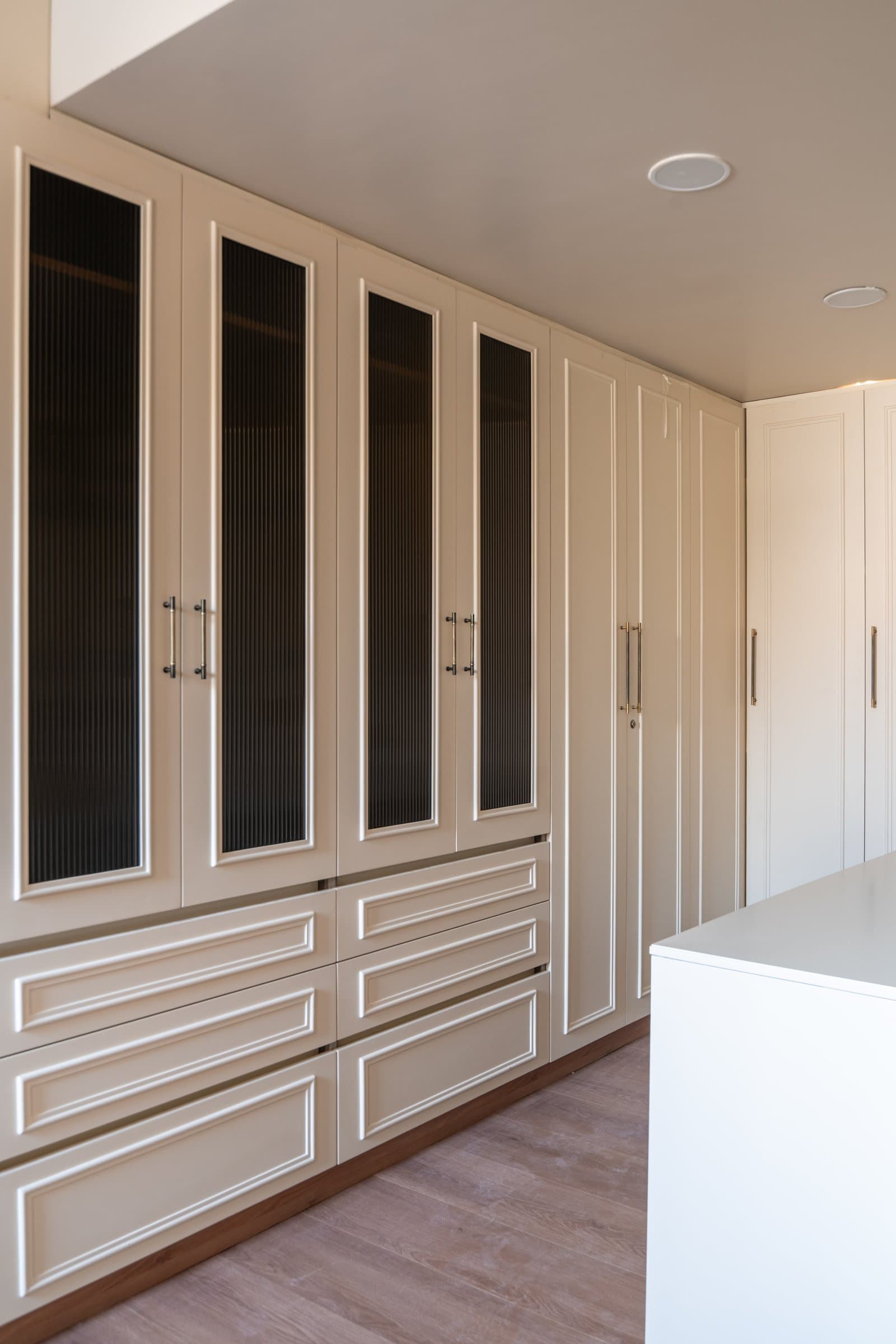 A closer look at the wardrobe interiors, where reeded glass inserts carry the home's classical vocabulary into utilitarian joinery