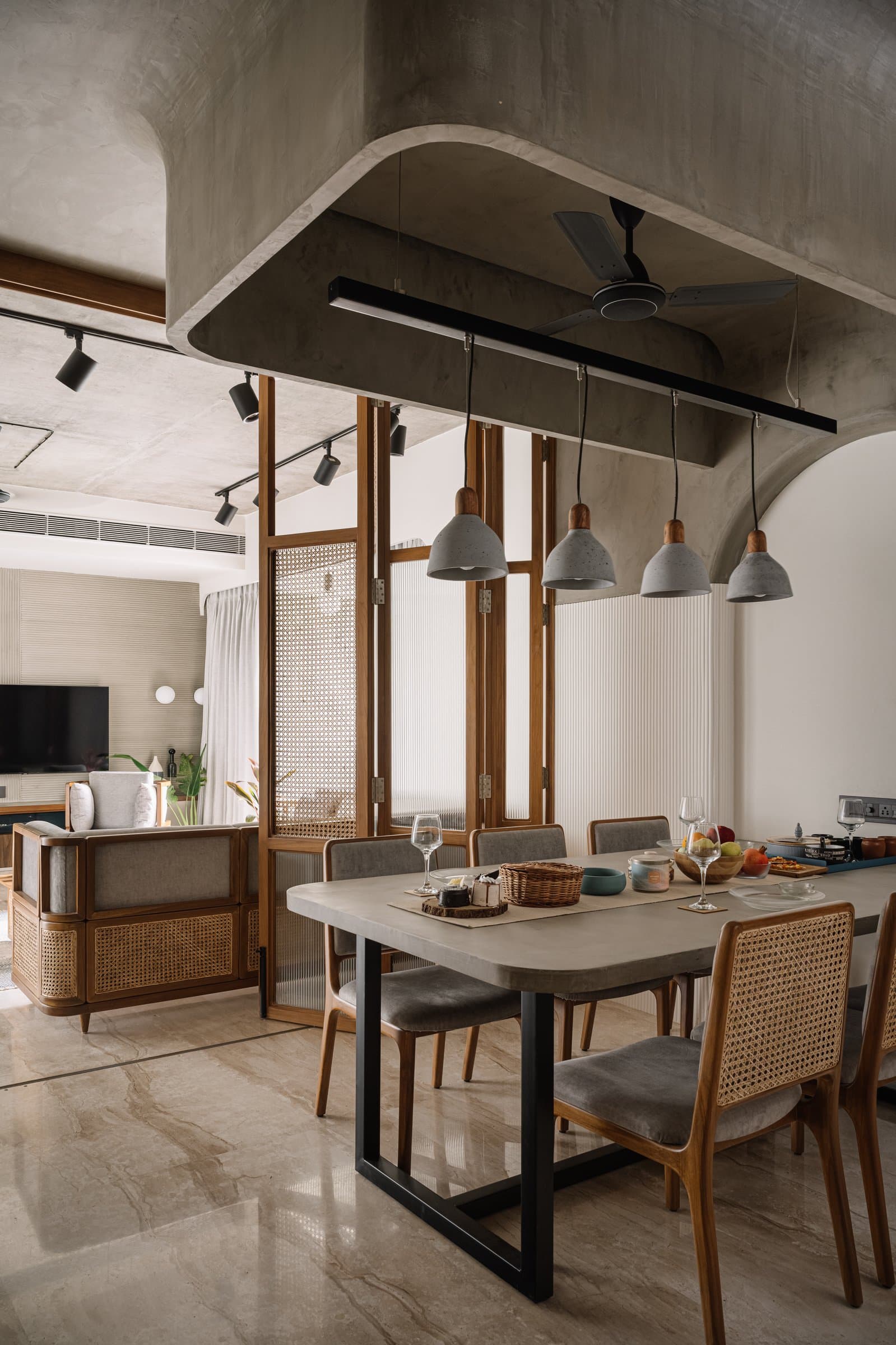 The dining area beneath its vaulted concrete bulkhead, concrete pendant lights descending in formation