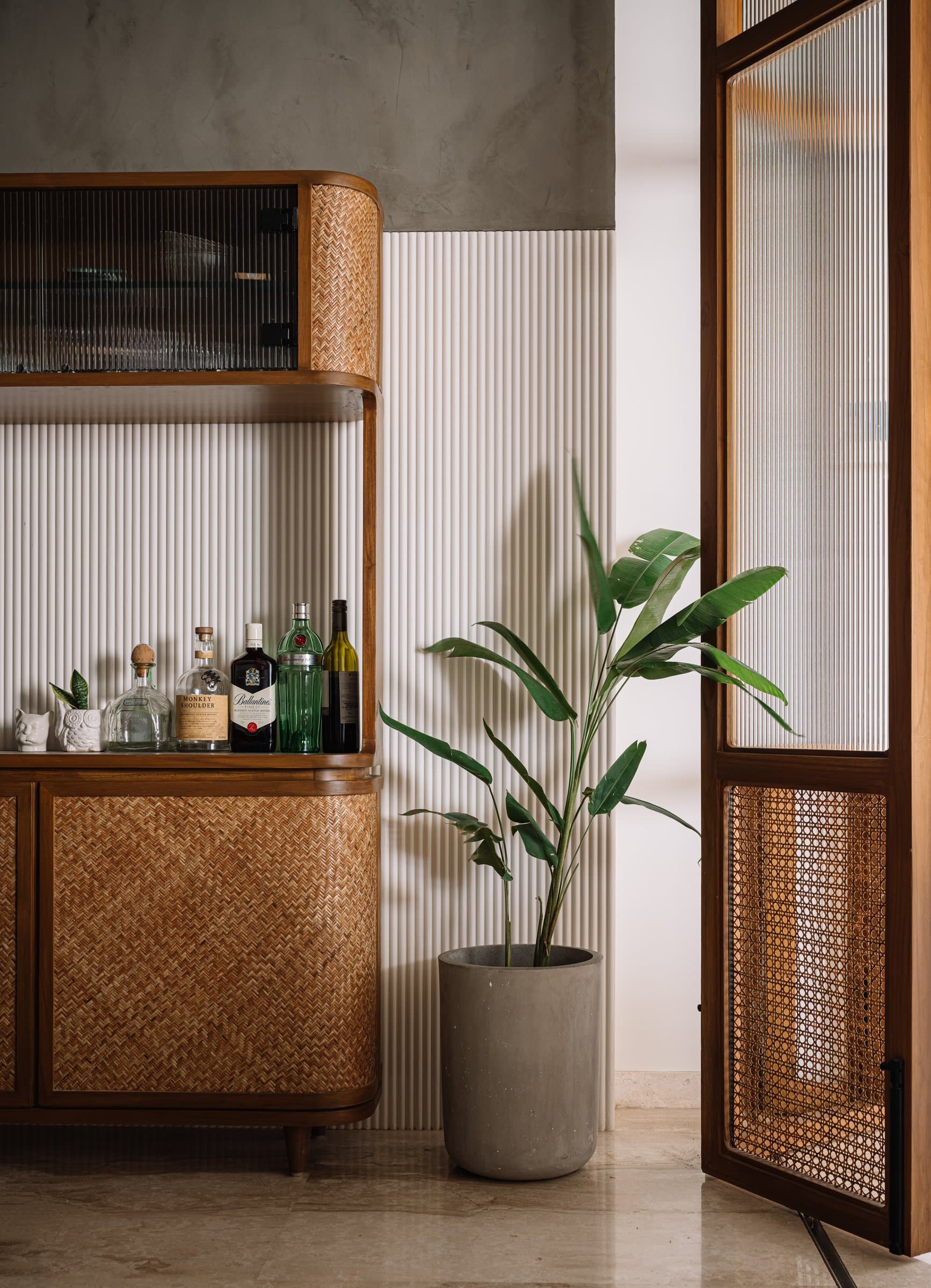 Detail of the bar and crockery unit, herringbone cane panels within rounded timber joinery