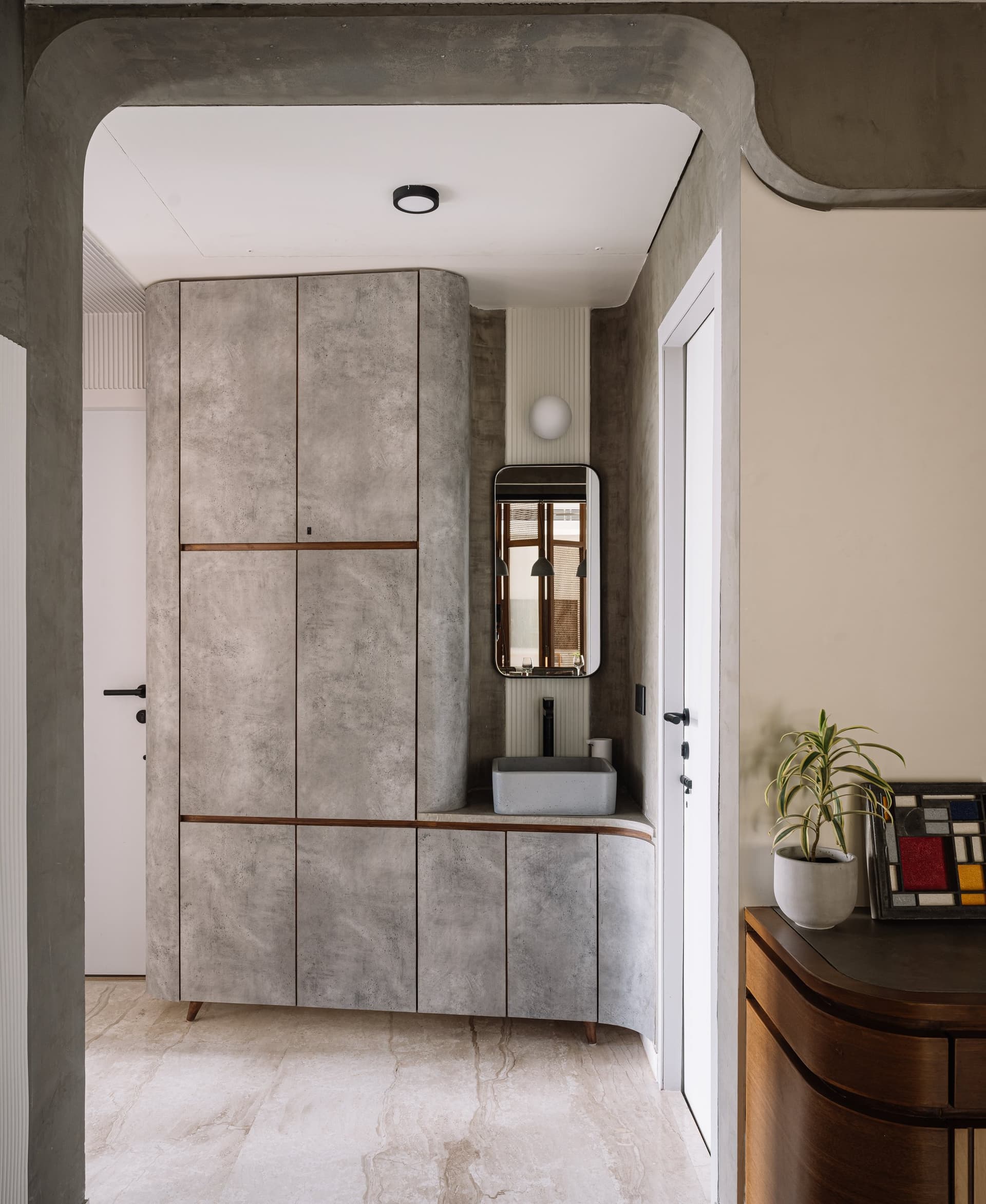 The common passage: a cement-plastered storage and wash-basin unit with curved corners, treating circulation as inhabitable space