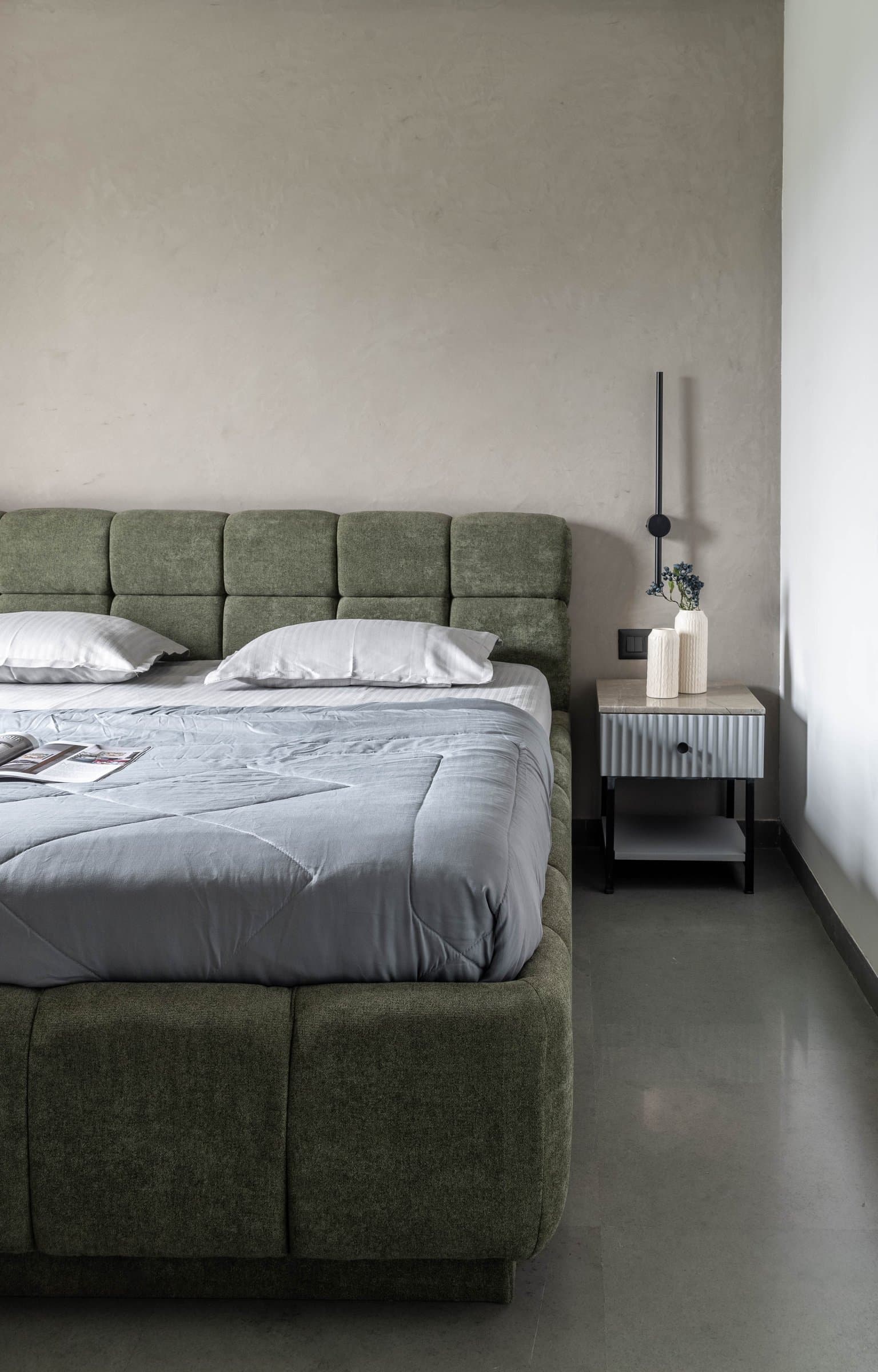 The master bedroom's quieter side, where plaster and a fluted nightstand provide the only surface interest