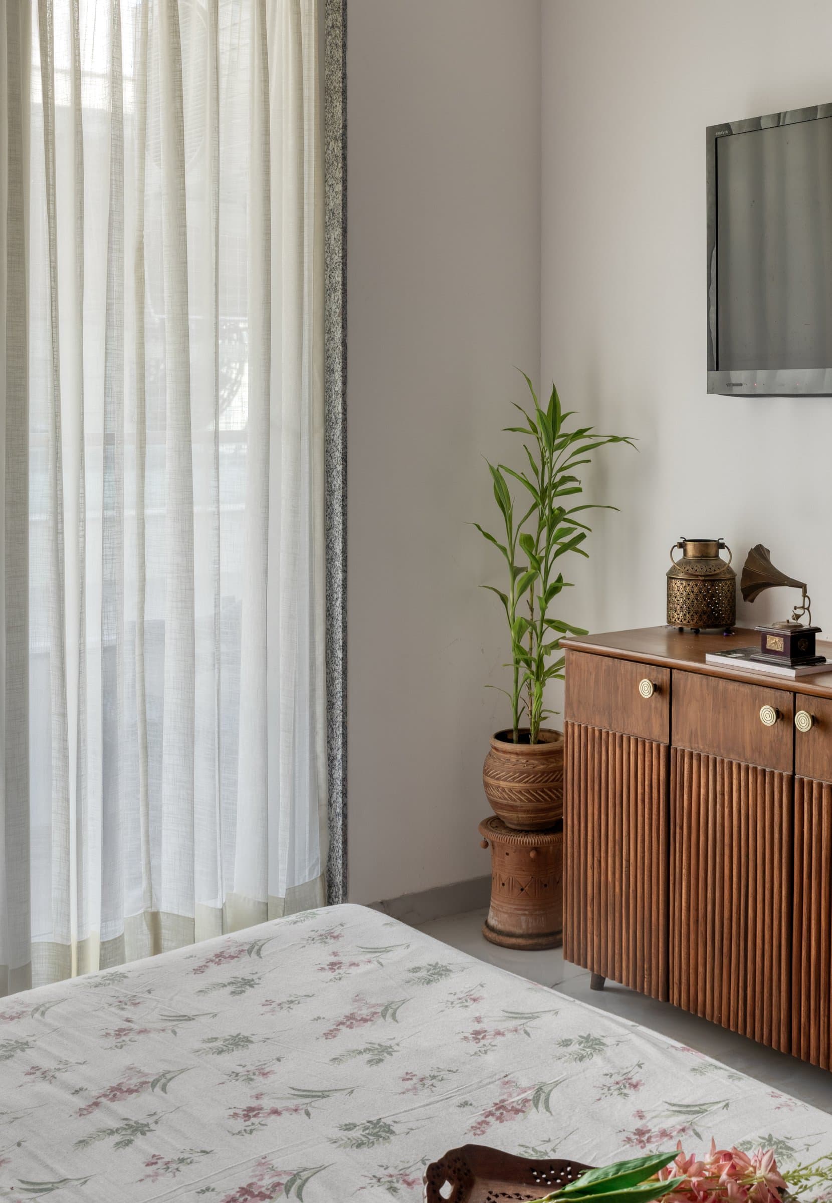 The quieter side of the master bedroom, where sheer curtains and a fluted timber console provide visual relief