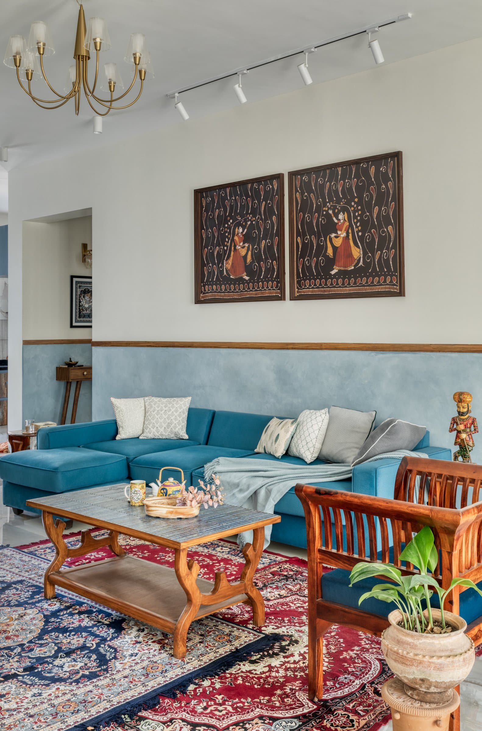 A closer view of the living area's layered composition: track lighting, brass chandelier, and botanical figurative art