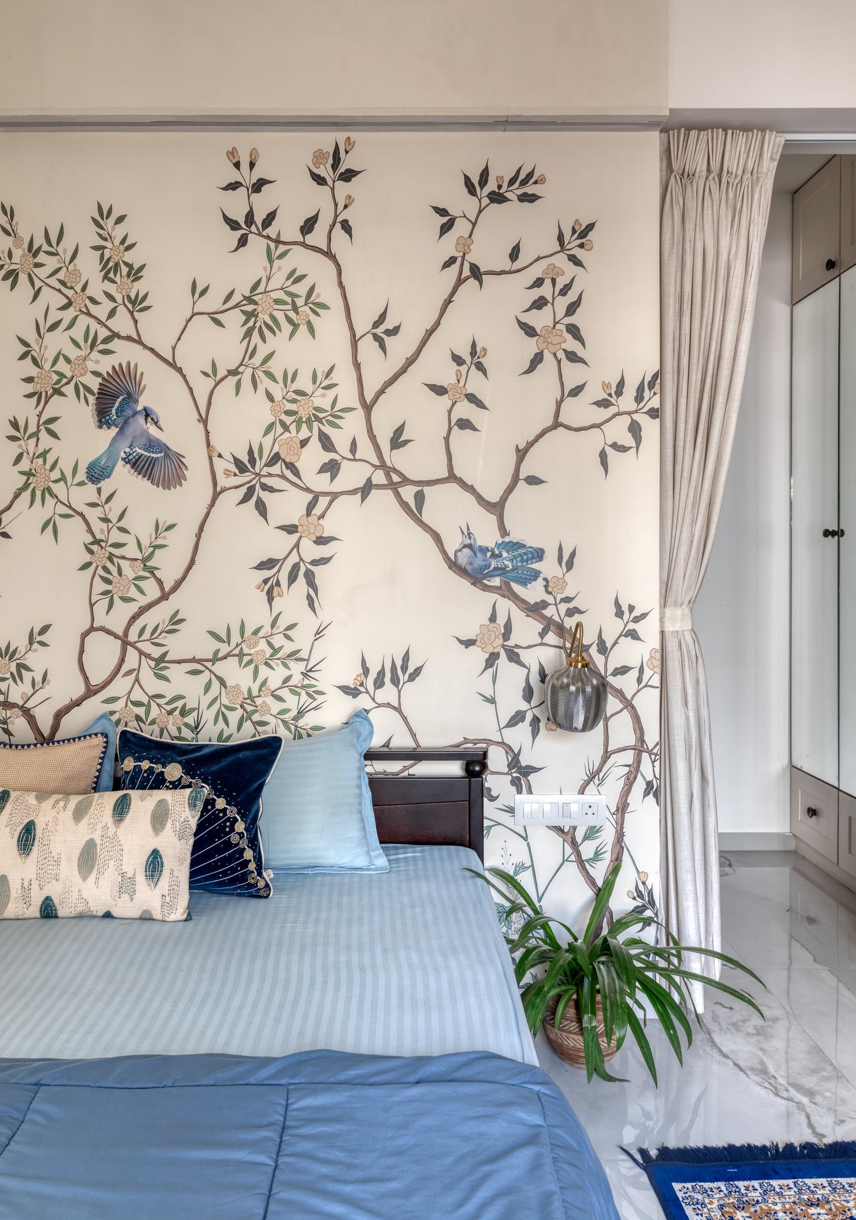 A botanical mural of flowering branches and birds transforms the third sleeping space into something lighter and more narrative