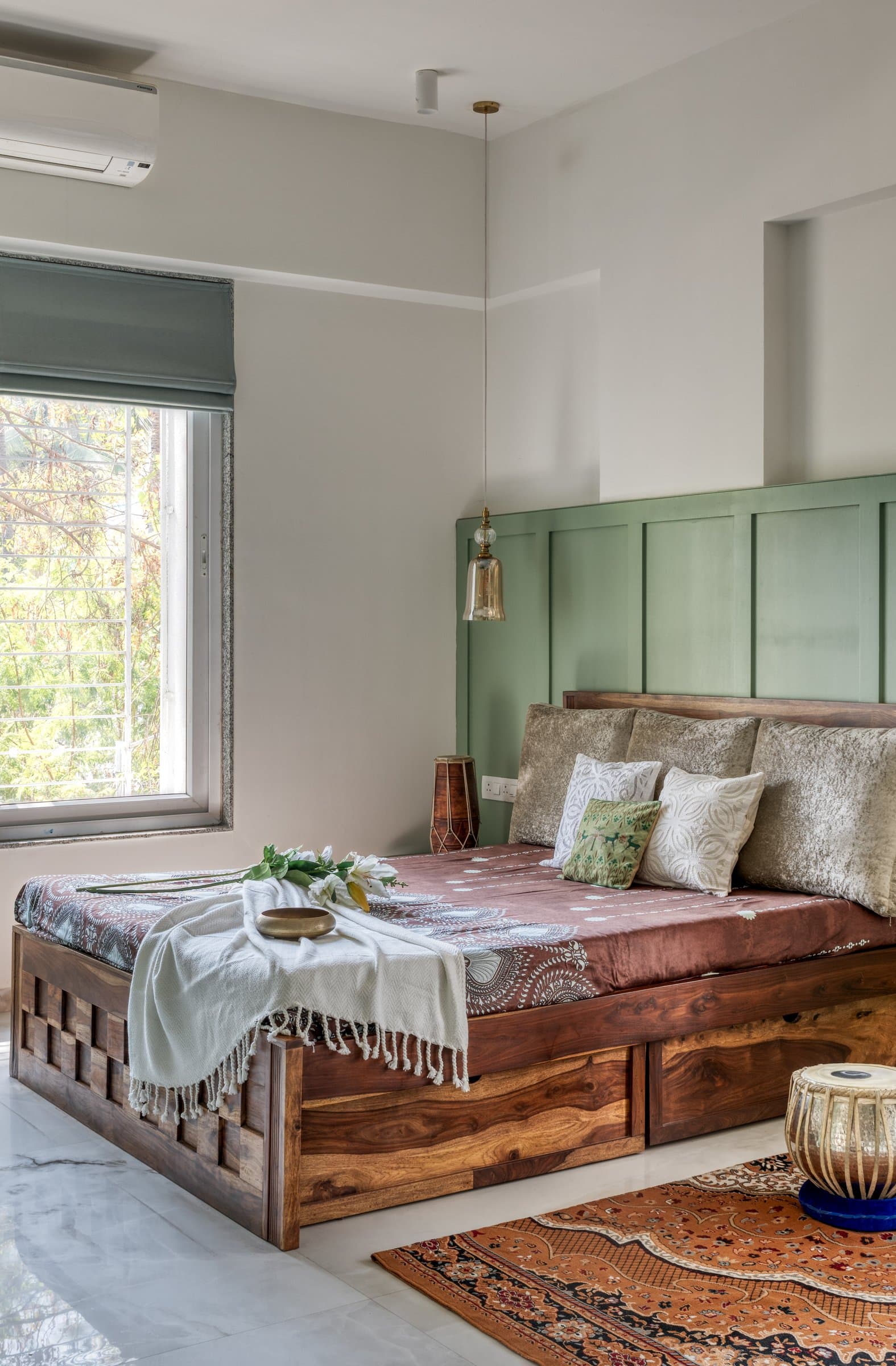 The second bedroom in sage green, where a panelled headboard and solid sheesham bed set the room's grounded tone