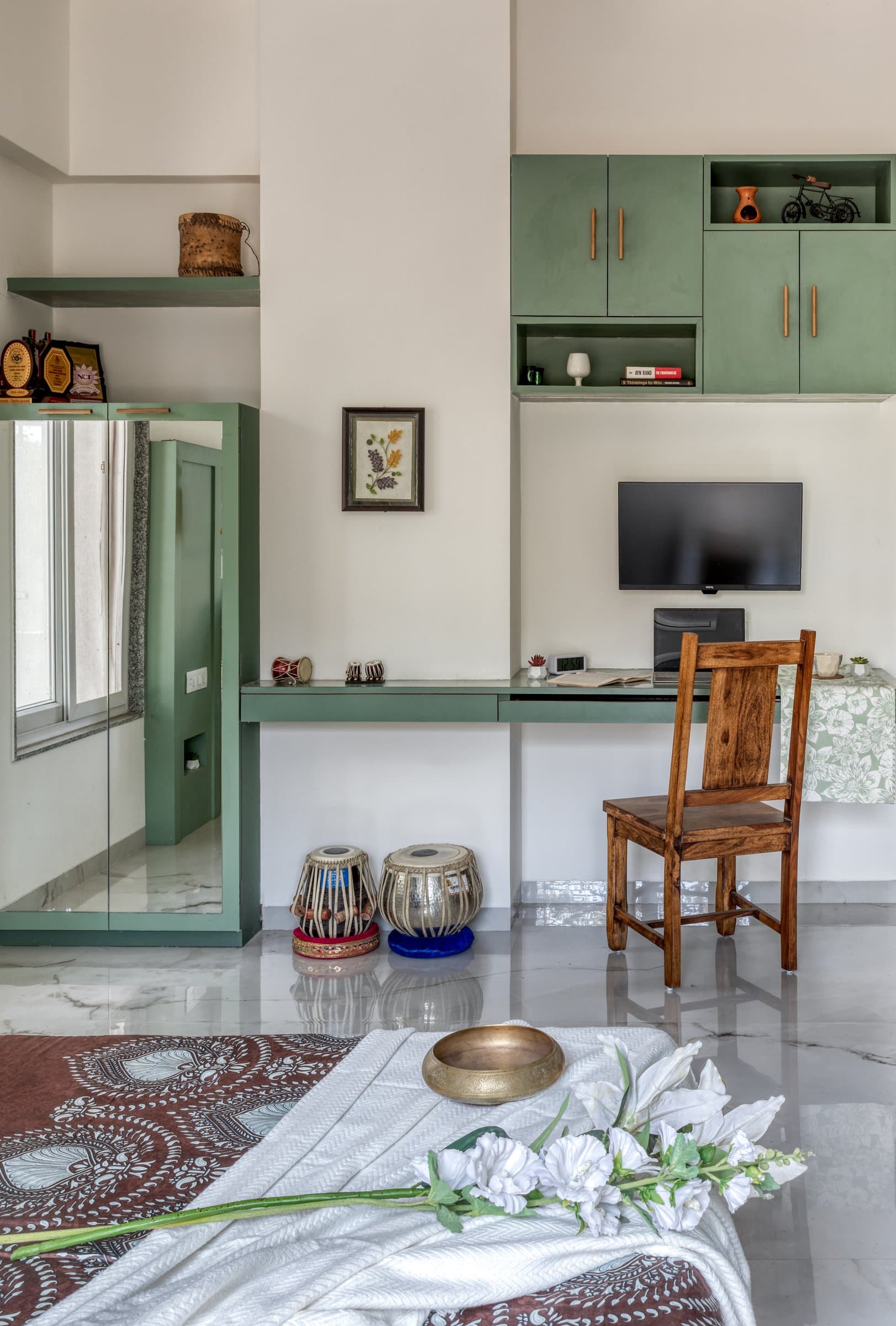 A study corner within the green bedroom, its floating desk and overhead storage unified by a single restrained palette