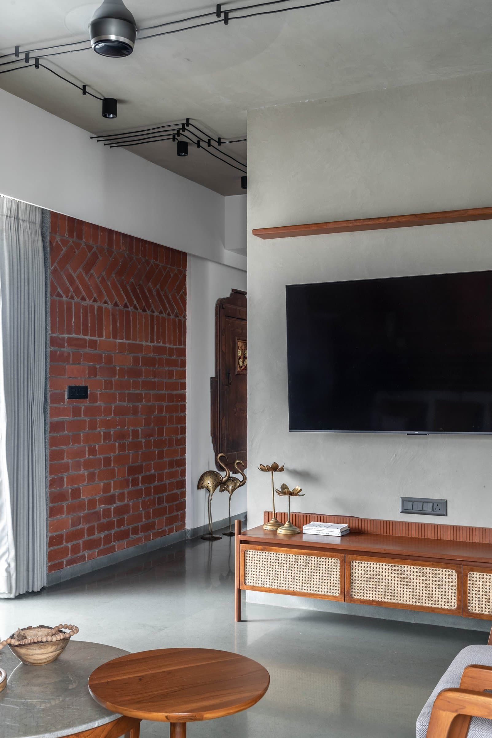 The television wall and cane-panelled console, where a continuous timber shelf links living room to kitchen