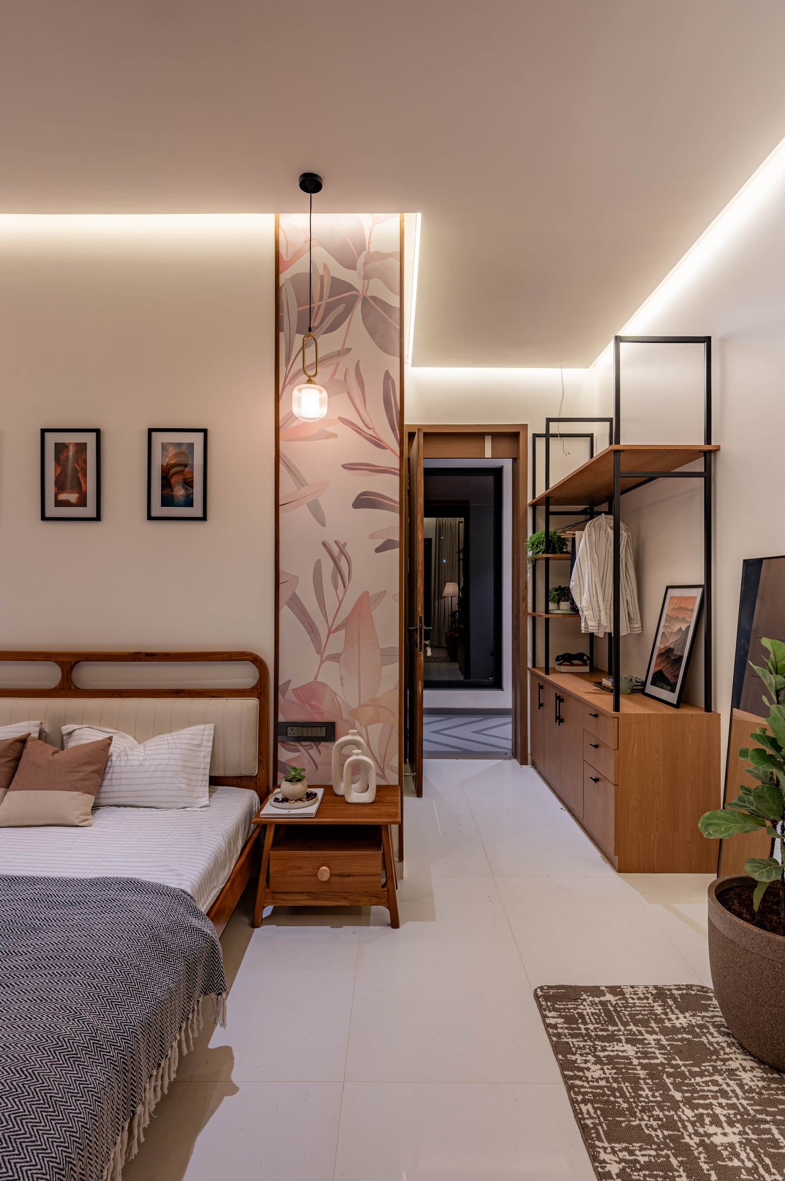 A second bedroom shifts to blush tones, with a botanical accent wall and open steel-and-timber wardrobe