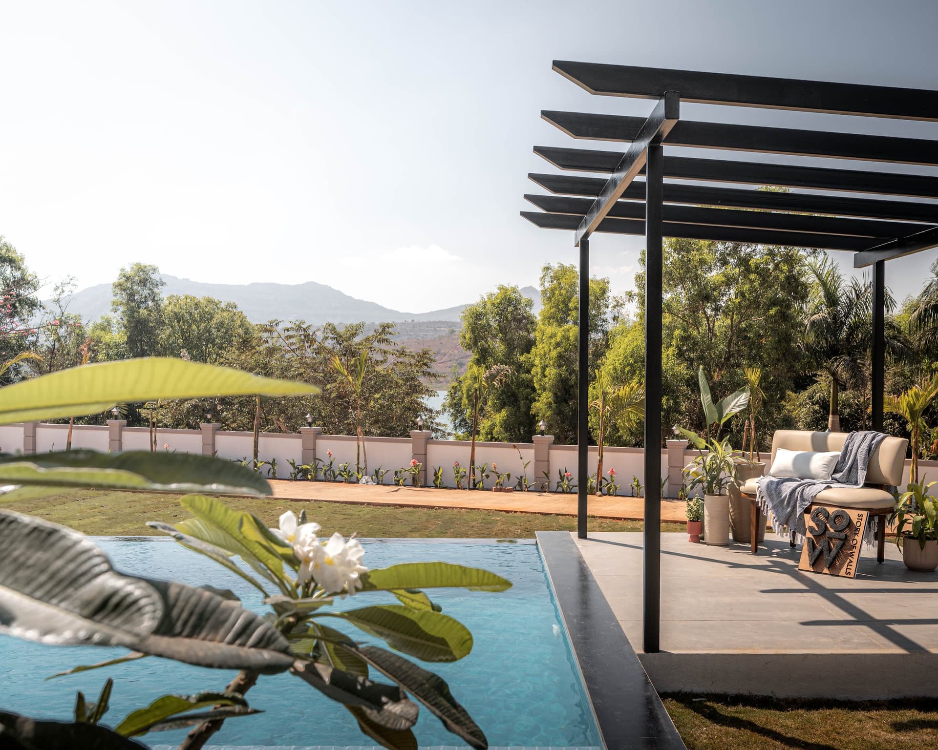 The poolside pergola, where plumeria blossoms and the Sahyadri hills share the same frame