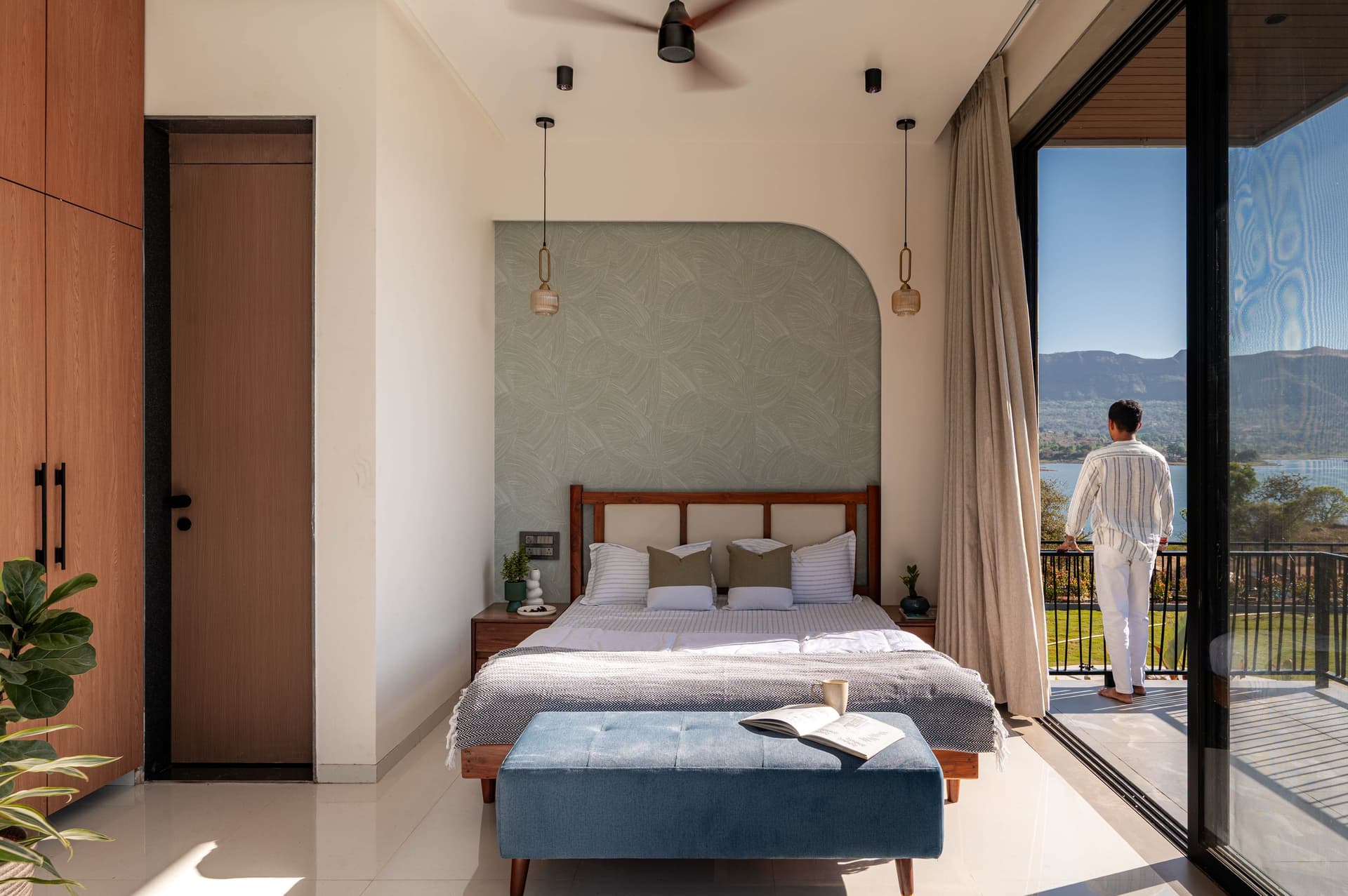 The sage bedroom, its arched headboard panel and full-width glazing connecting sleep to the Sahyadri